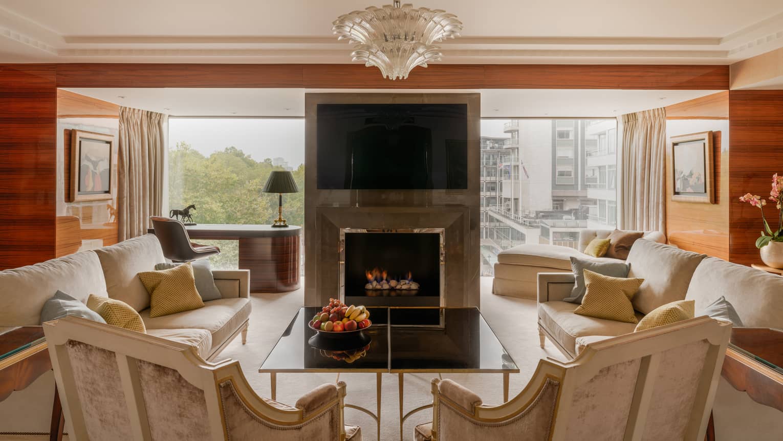 Elegant living room of Presidential Suite, with two sofas and two arm chairs, fireplace, TV and chandelier at Four Seasons Hotel London