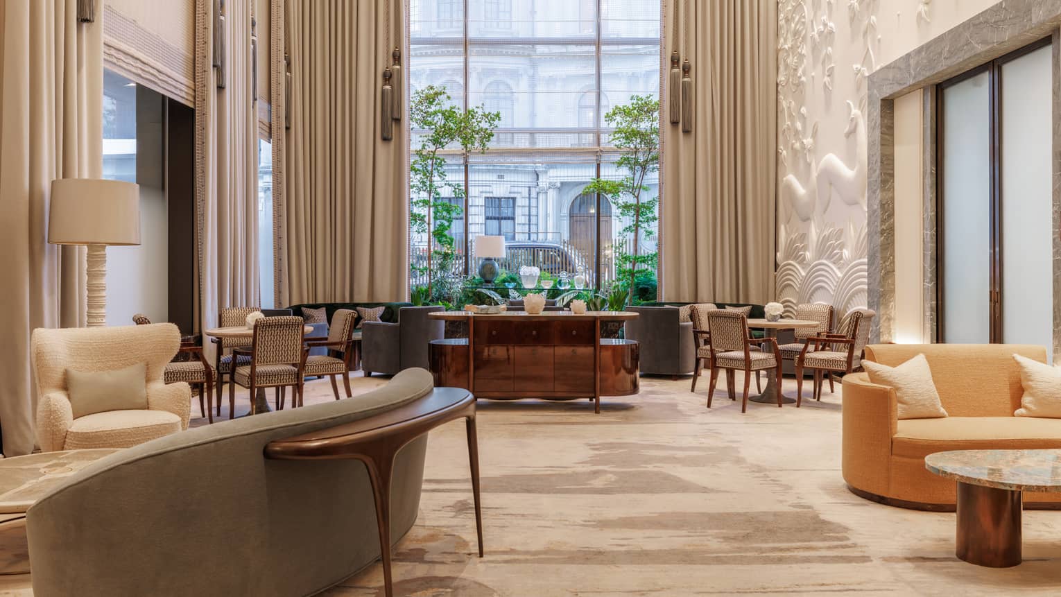 A bright, airy and spacious indoor lounge space with neutral-toned decor, comfortable seating, tables, and large windows