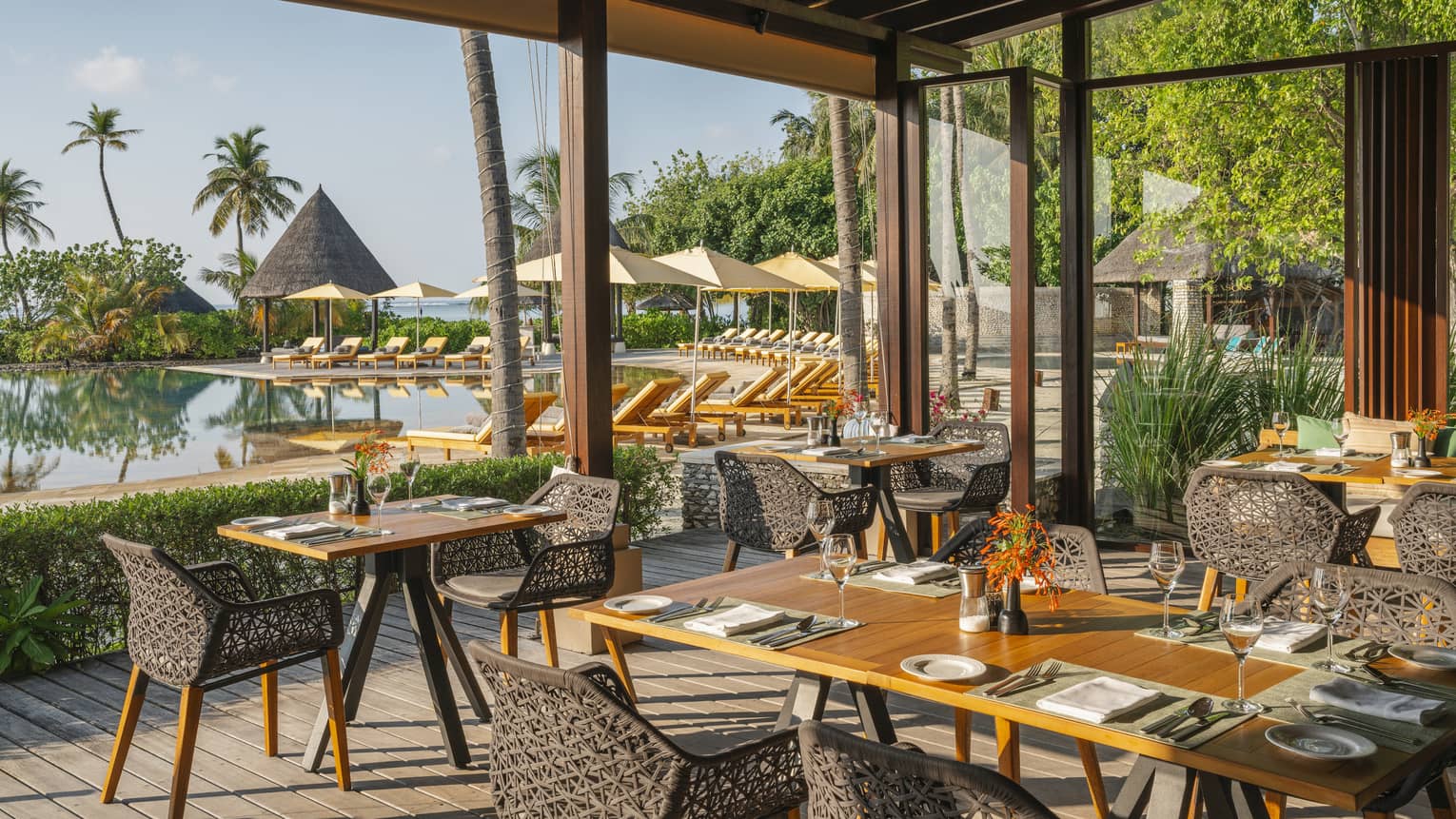 Open-air restaurant Caf� Huraa with rattan chairs and blonde wood tables, overlooking the pool