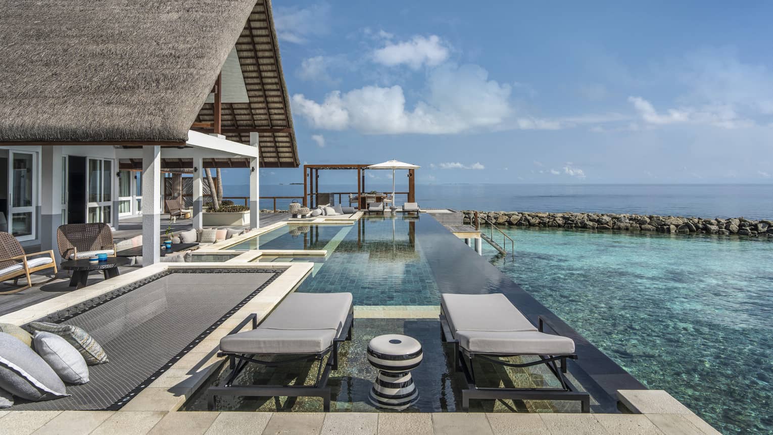 Private pool deck of overwater villa, with overwater lounge net and two chairs