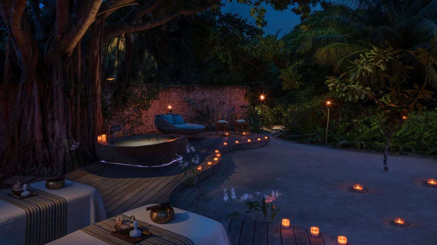 Candles along sand beach, spa patio, hot tub at night