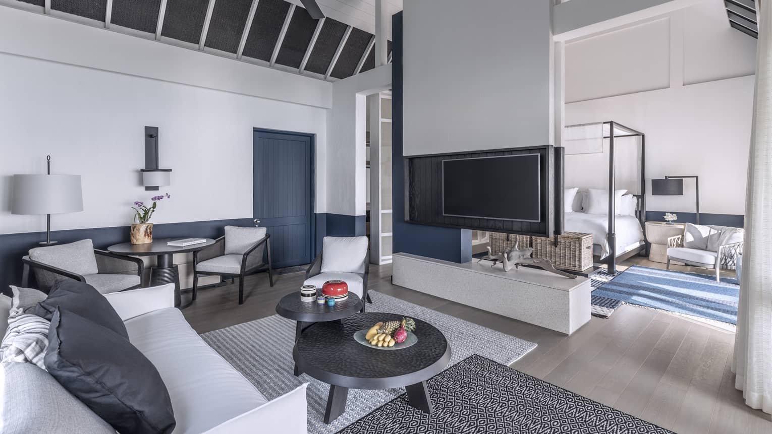 A brightly lit, cozy living room with a television, couch and access to the bedroom
