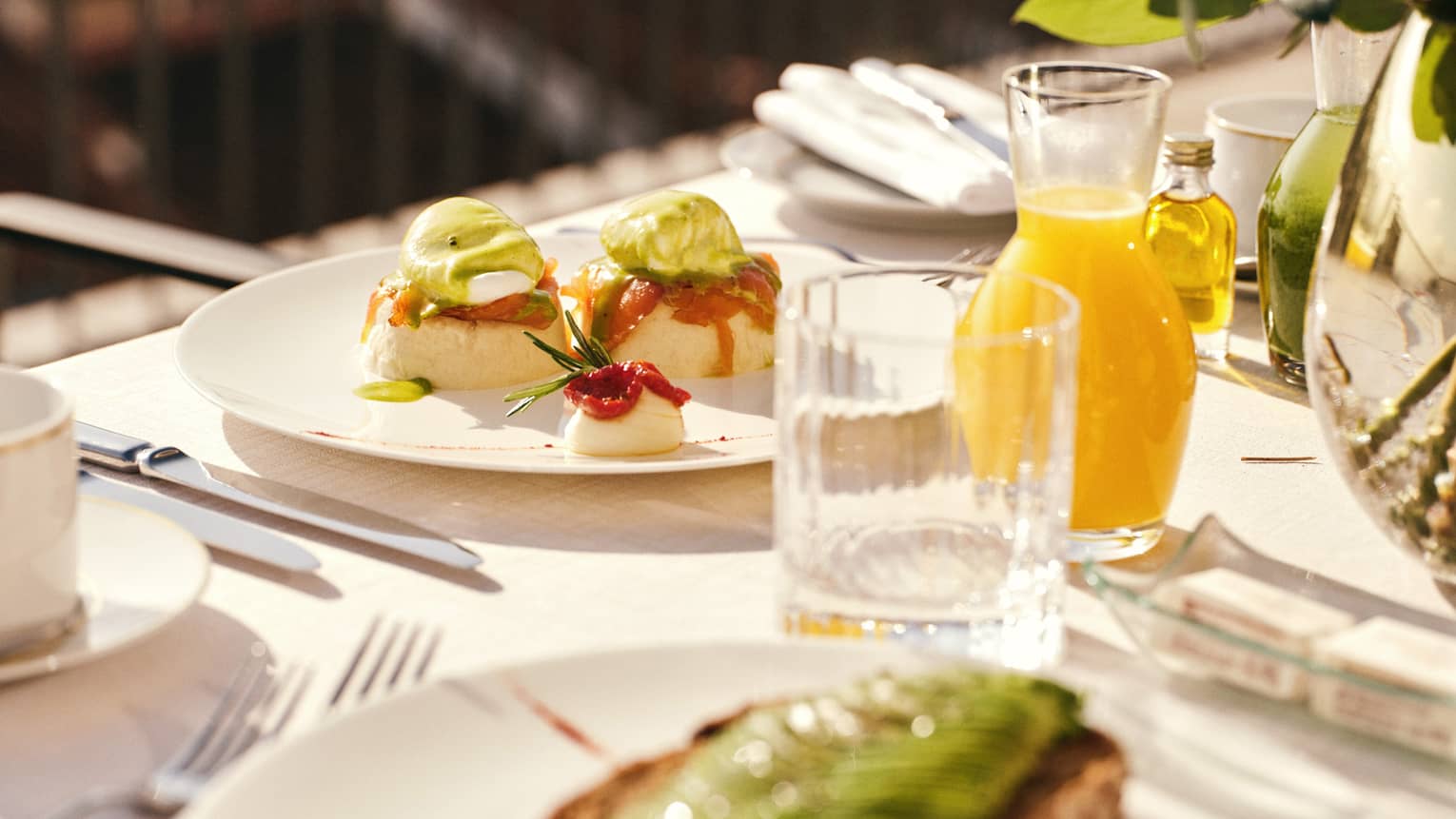 White plates topped with colourful brunch dishes on a table with glasses and a carafe filled with orange juice