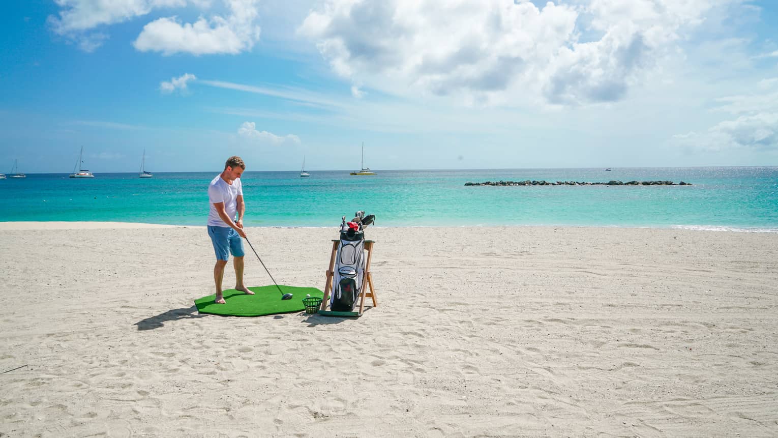 A man golfing on a clean beach near the ocean.