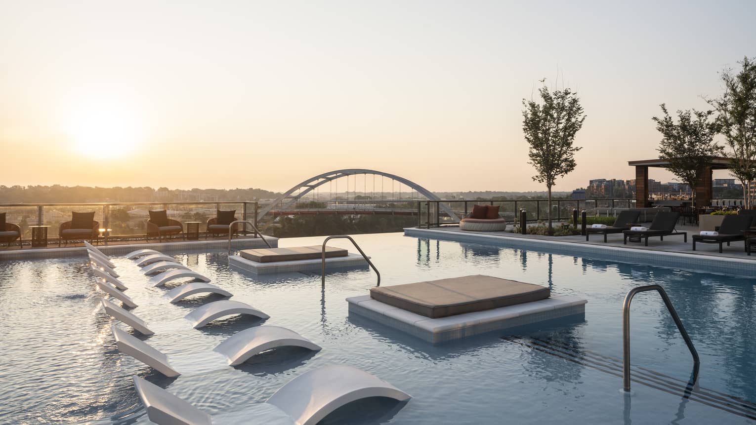 Rooftop pool with the sun setting in the background.