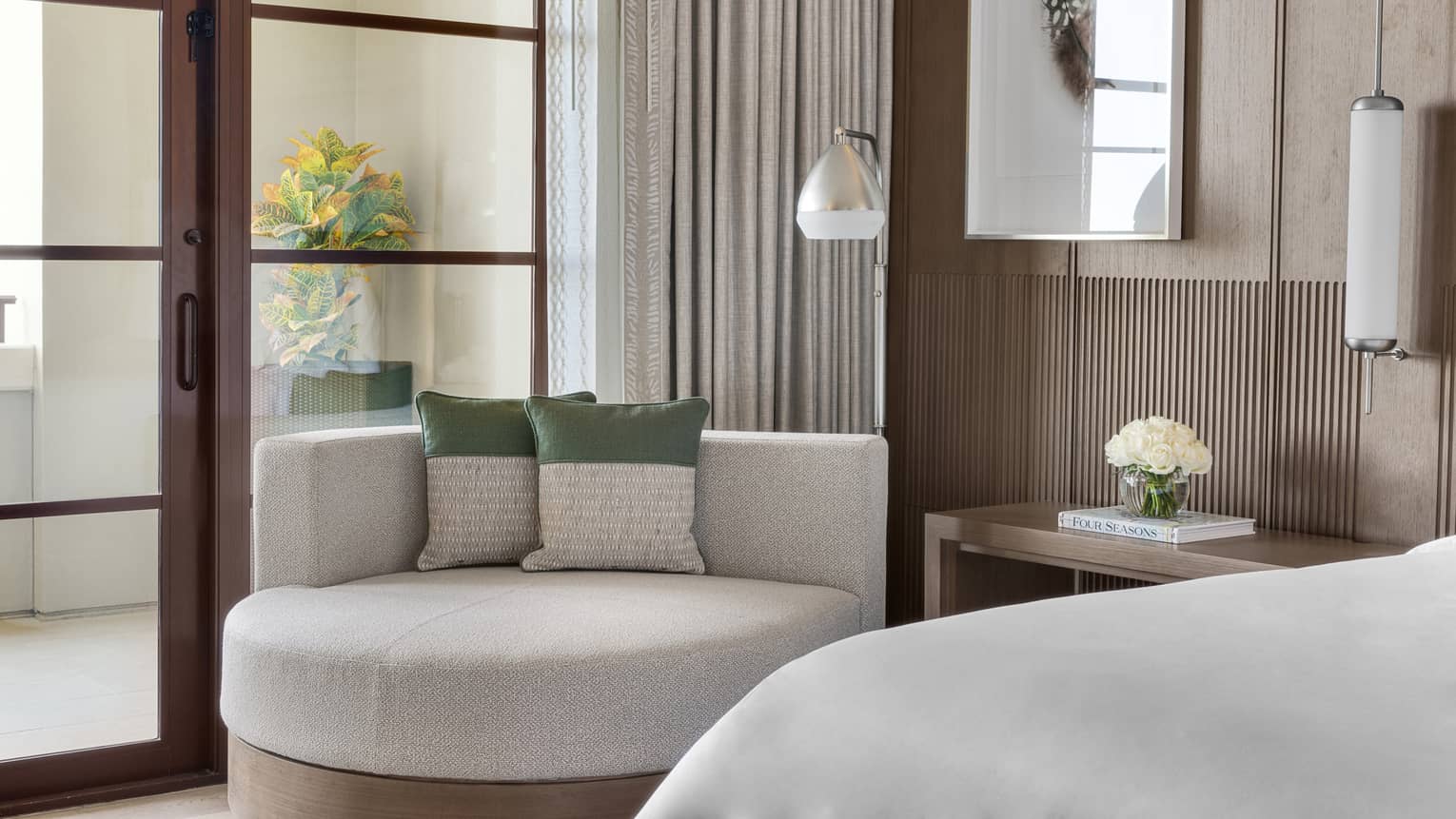 Modern chaise next to a bed and glass door leading to outdoor balcony