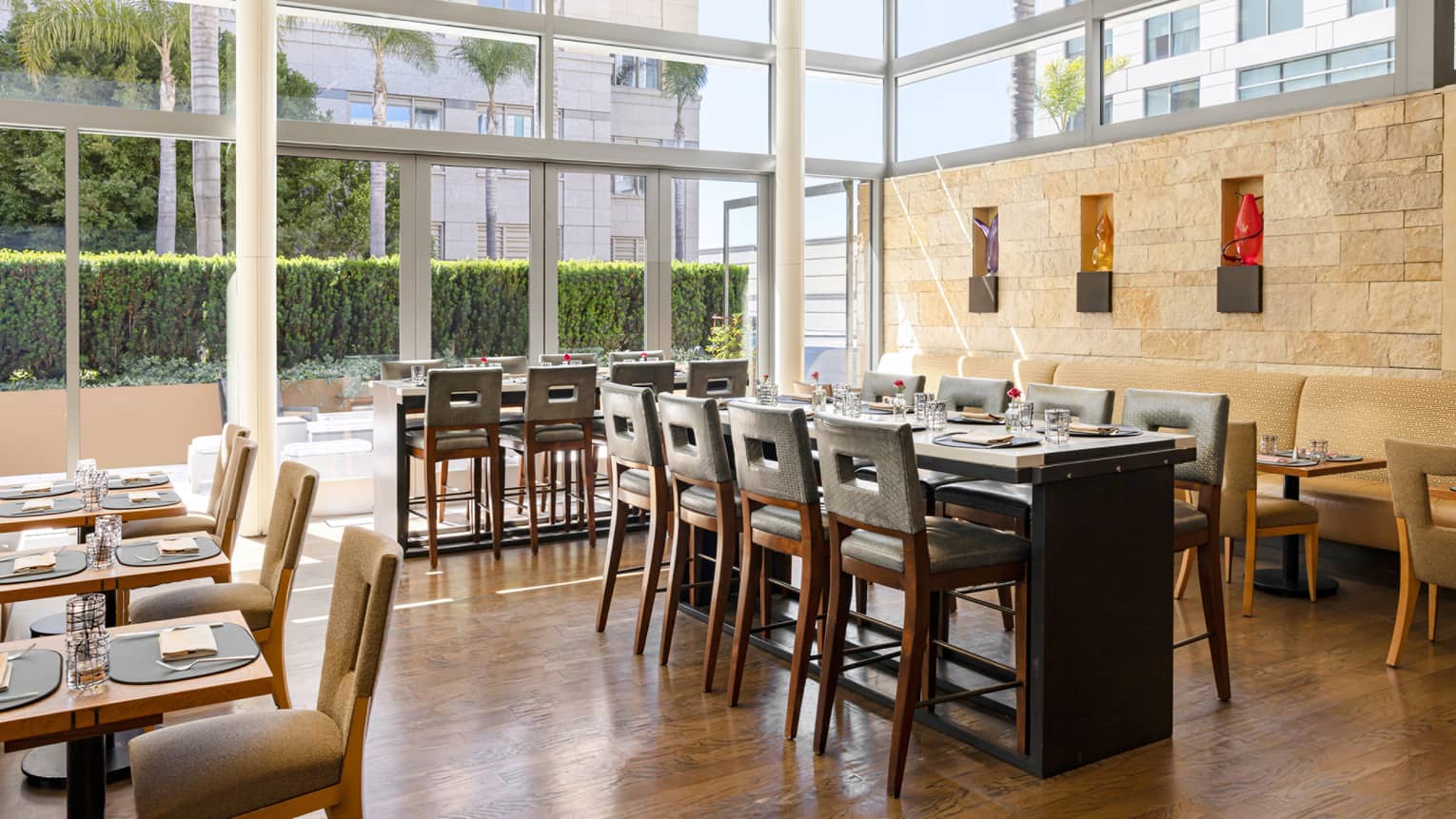 The interior of a restaurant with light features and large windows, dark brown chairs and tables.