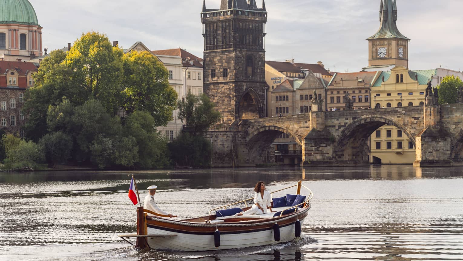 A woman on a boat floating down water near an old city.
