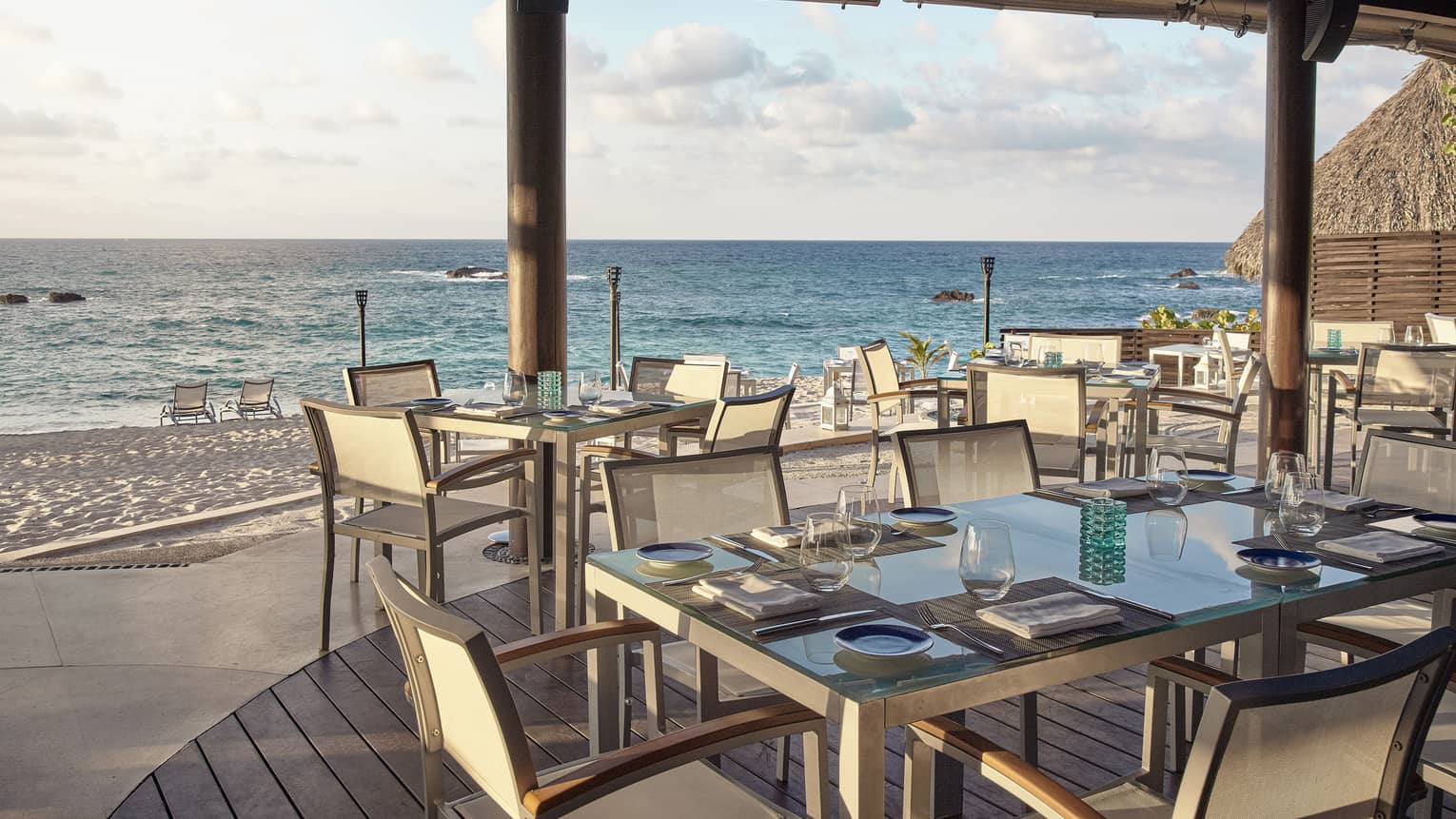 Restaurant tables of four sit under wooden pergola, looking out to sea in Punta Mita