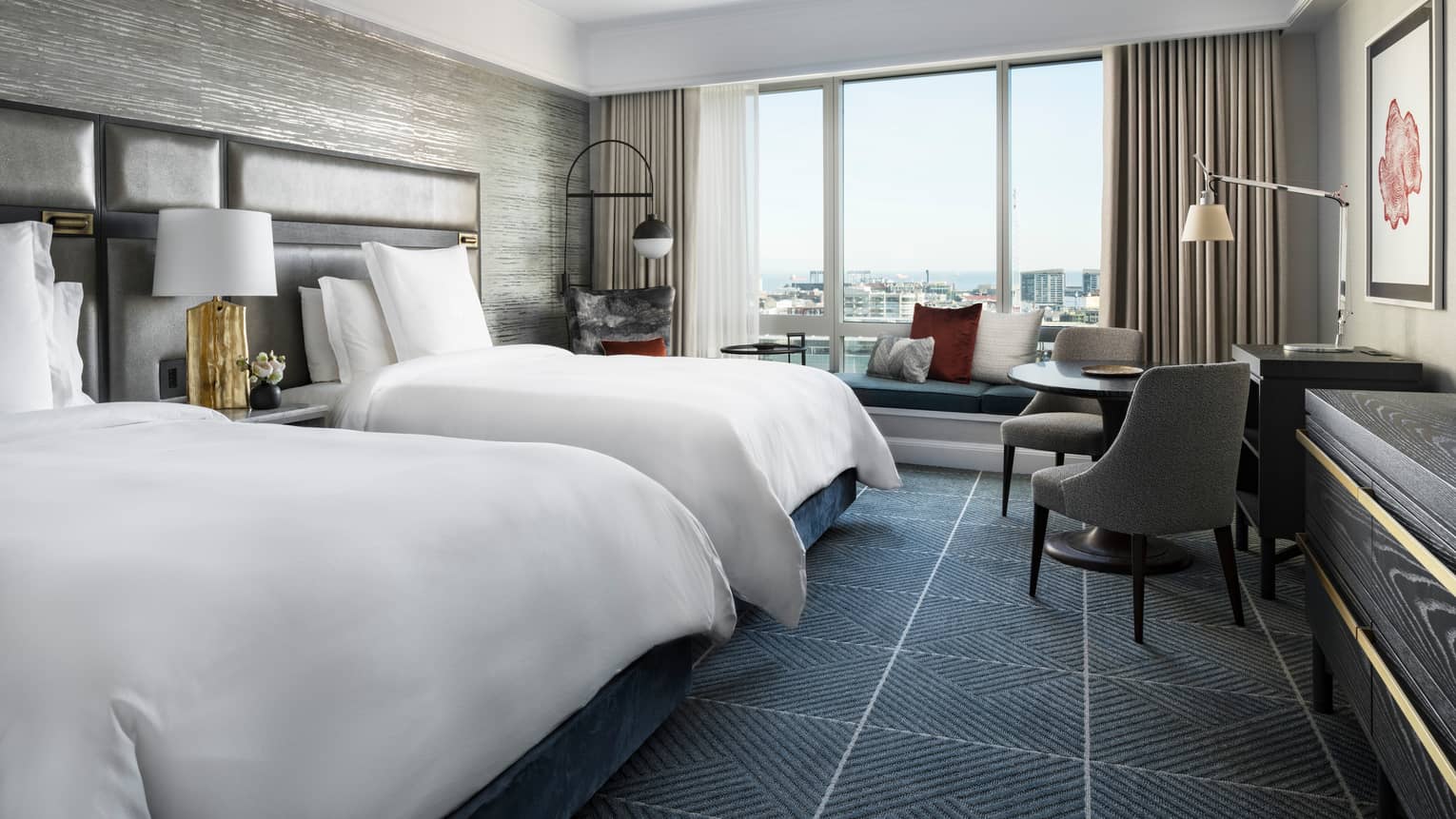 Room with two double beds, dark grid-like carpeting, large windows