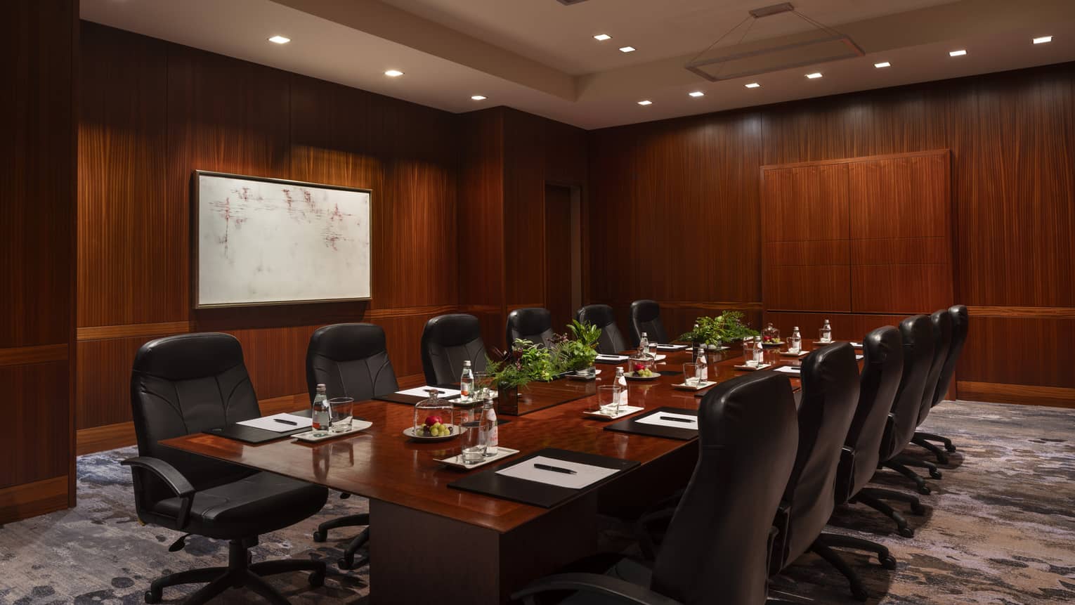 A boardroom with a large table with chairs.