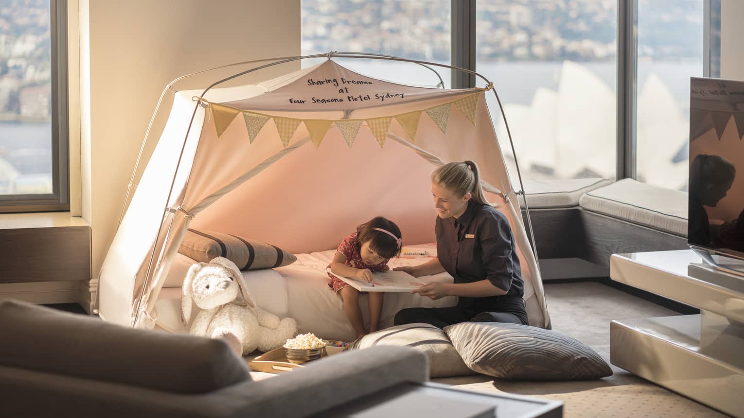 Little girl colours with help of FS staff member in an in-room tent