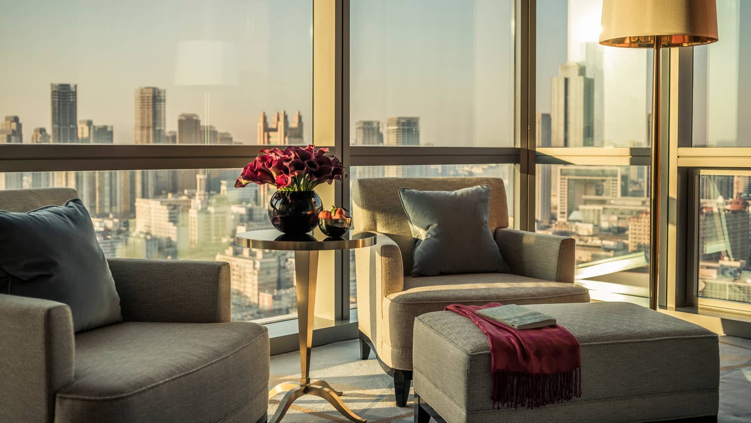 Club Premier Room plush armchairs, ottoman with scarf, book in front of floor-to-ceiling window