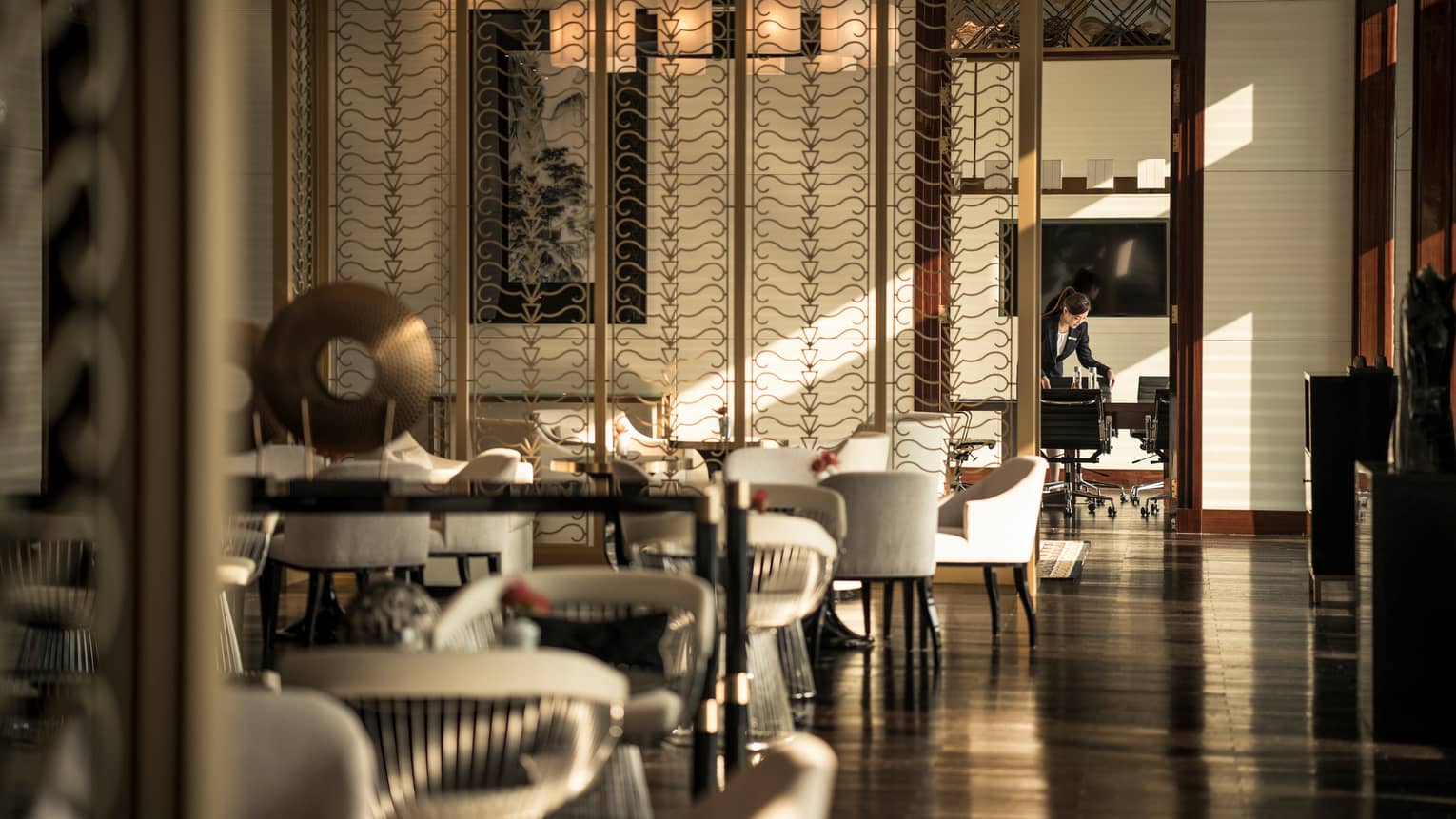 Executive Club Lounge white chairs around tables, wood floor, decorative bronze screen
