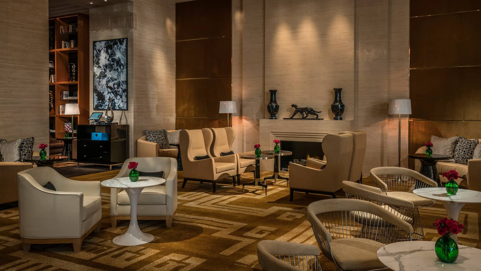 White armchairs, small cocktail tables in La Sala lounge, fireplace, modern art