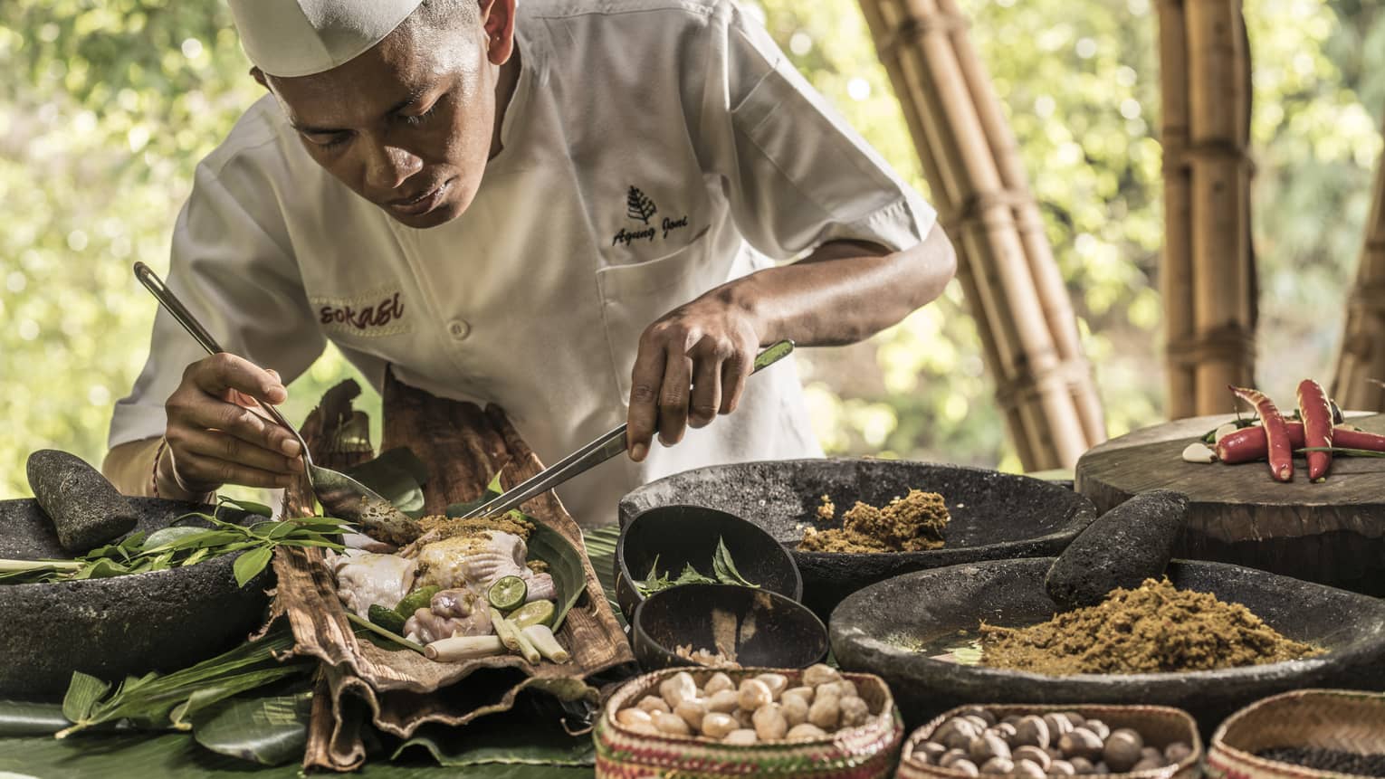 Chef Suta preparing a meal with meat, nuts, vegetables and spices in Bali
