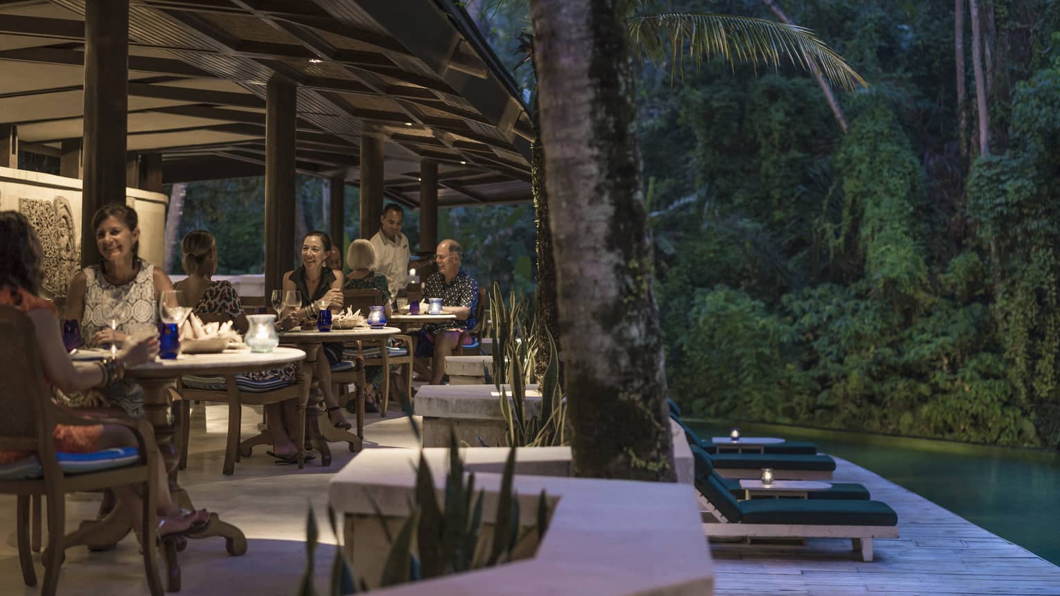 Guests enjoying dinner adjacent to a river in Bali