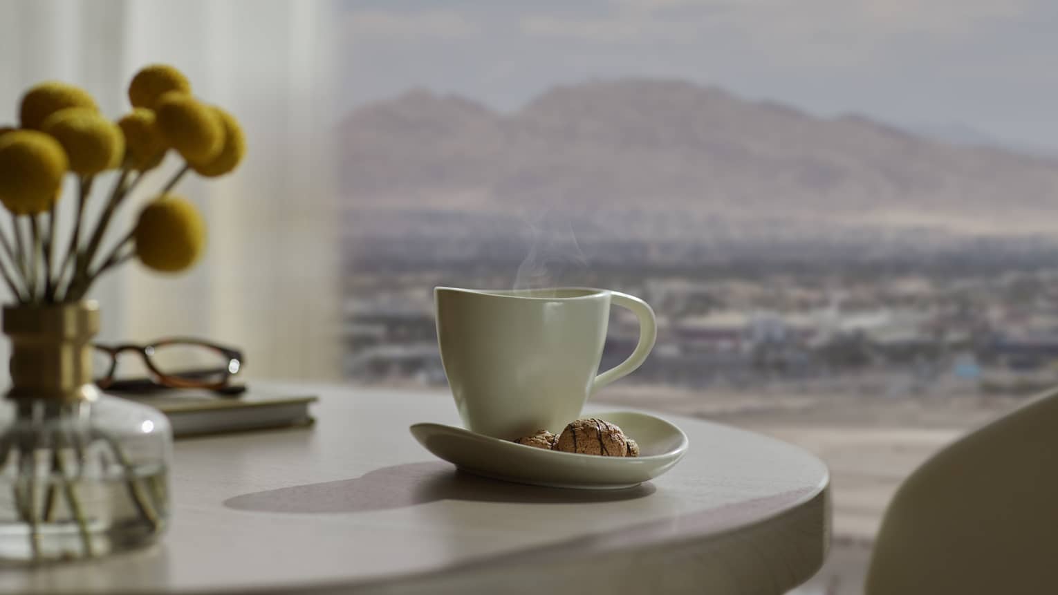 A table near a window looking out at nature, with coffees on the table.