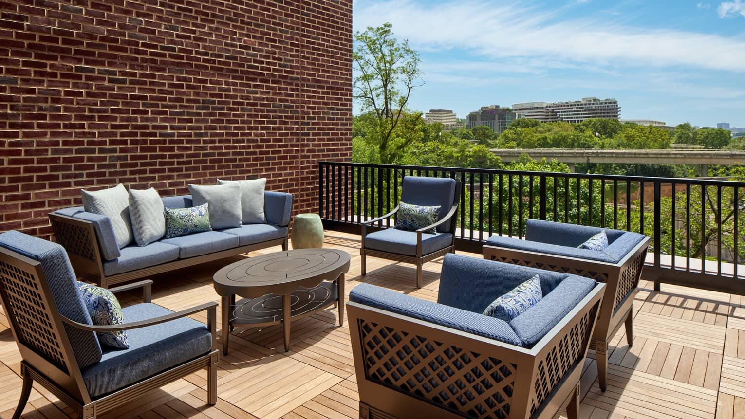 Large outdoor suite terrace with wooden floors and expansive lounge seating featuring dark blue cushions, at Four Seasons Hotel Washington, DC