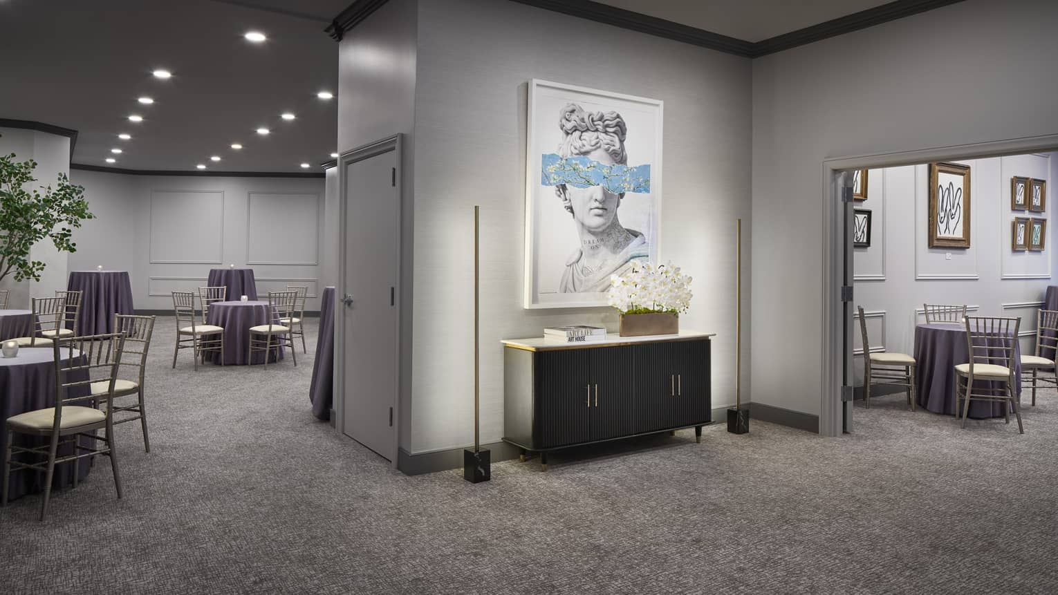 Reception room with a large painting on the wall and many tables and chairs.