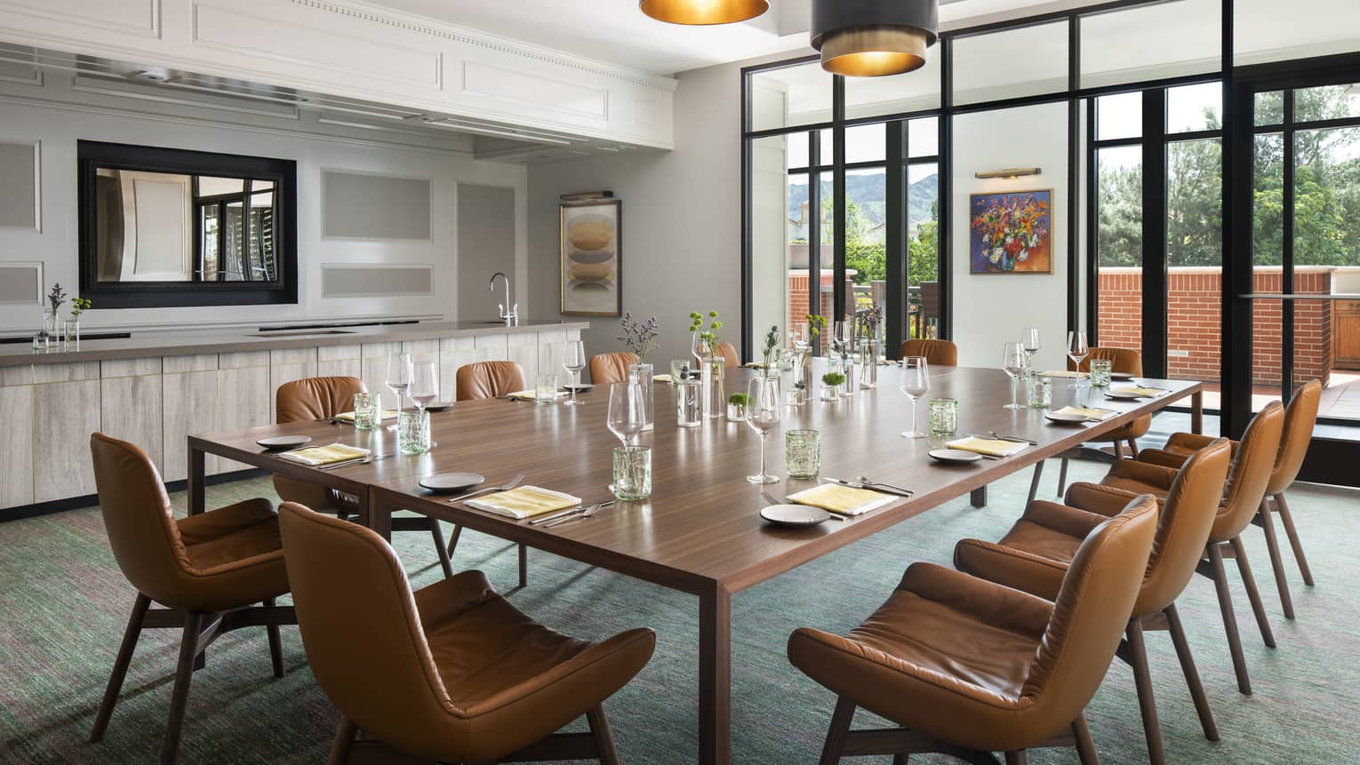 Light and airy dining room with dining table, leather chairs, artwork, overlooking patio and mountains 