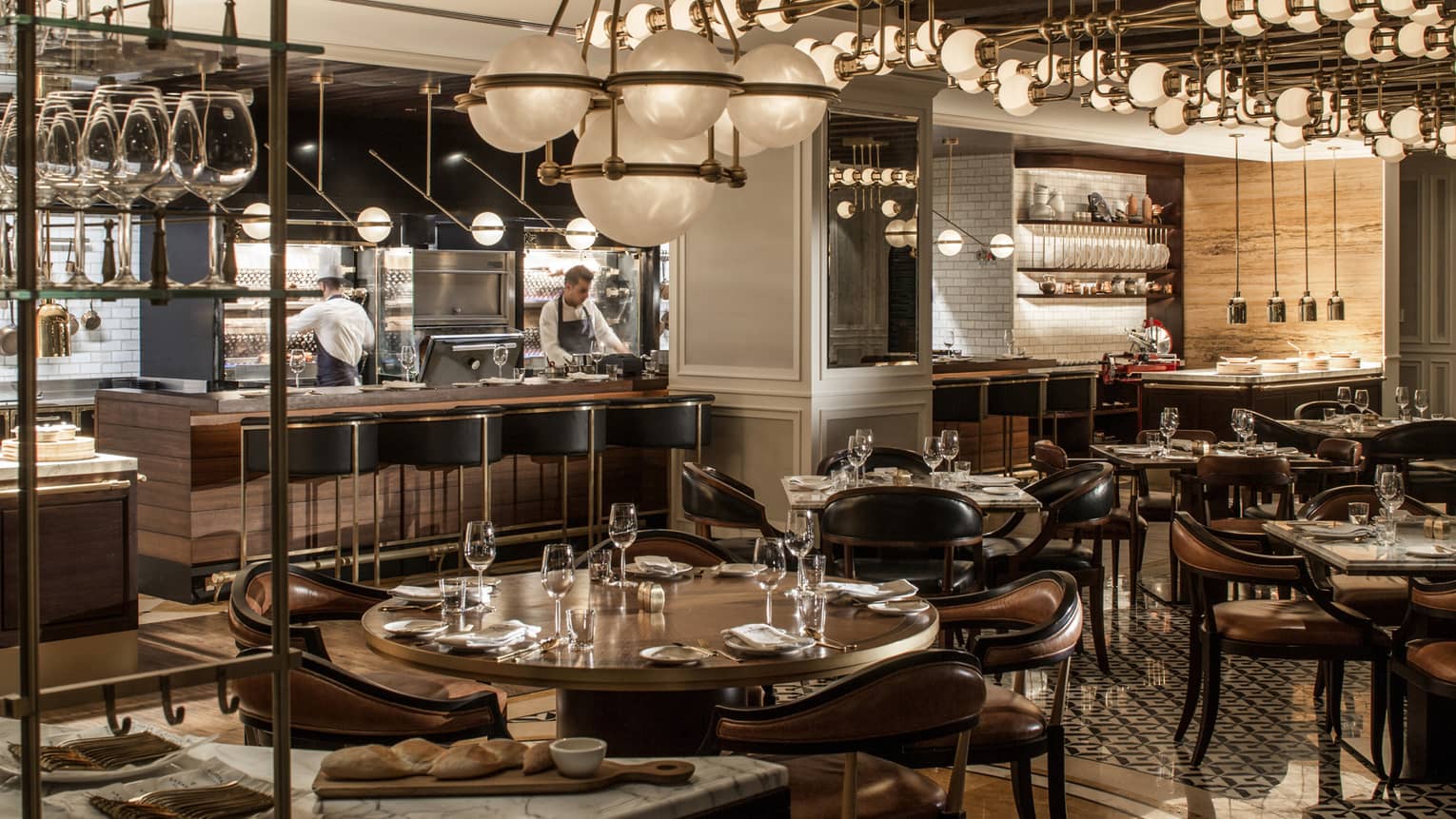La Capitale dining room with dark, wood decor, round tables and chandeliers, globe chandeliers, chefs in open kitchen
