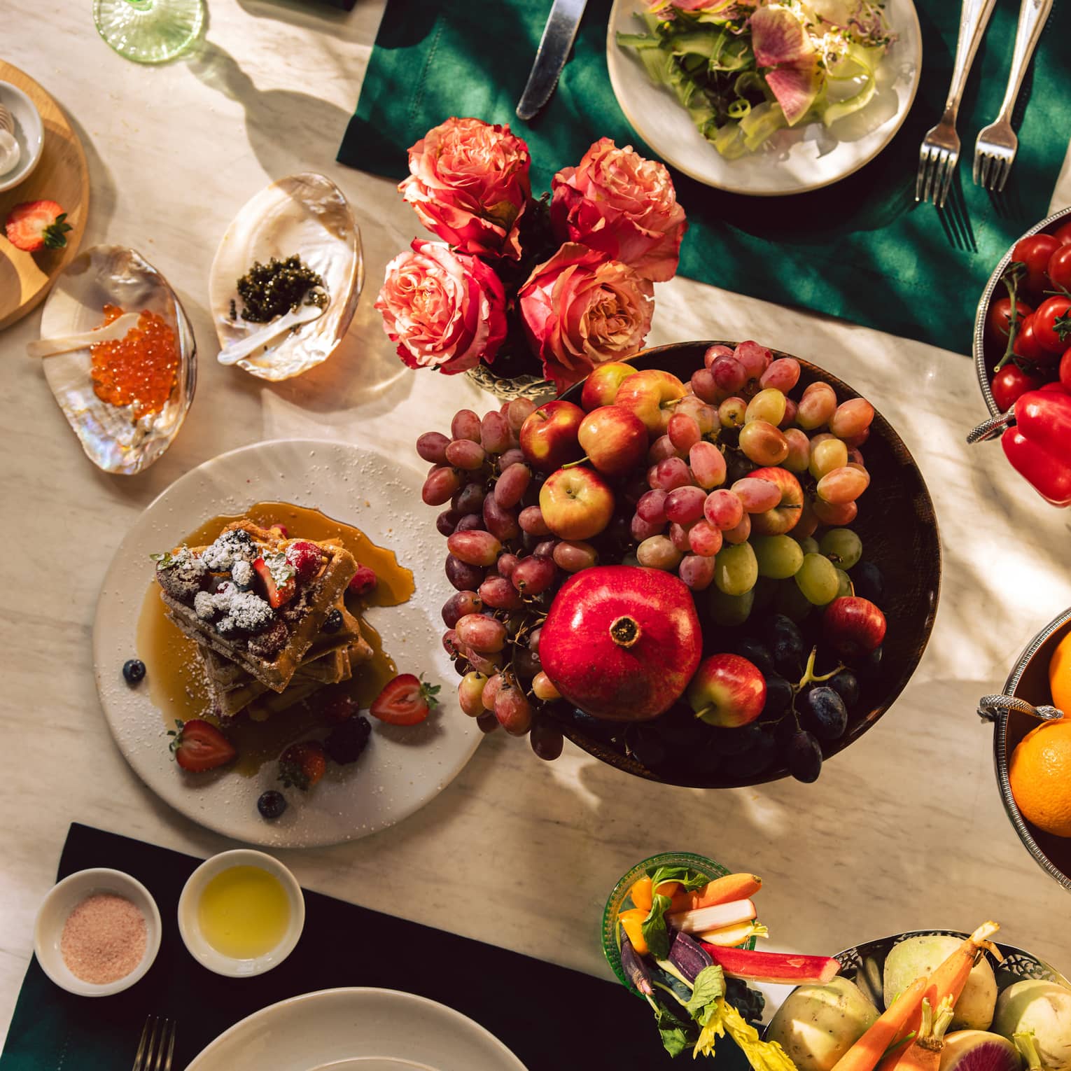 A dining table set with culinary dishes, including a fruit bowl and salad