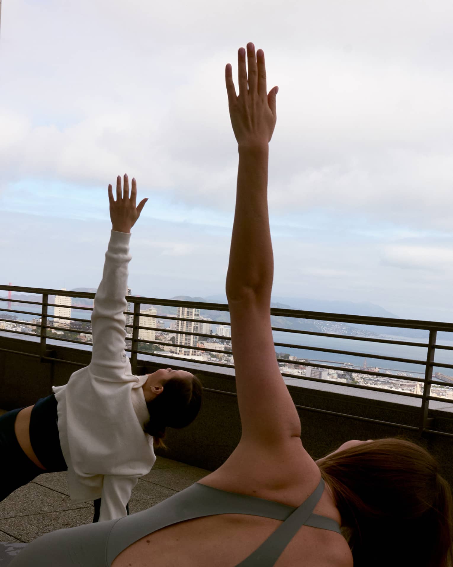 Two guests doing yoga on a rooftop with the sky in the background