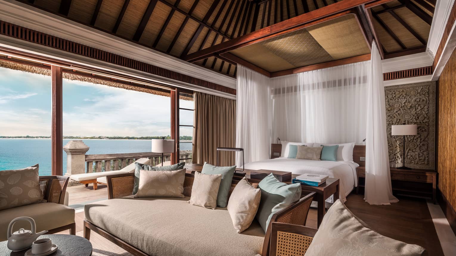 Family Premier Villa large bed with white drapes, sofa seating area, open wall to patio, ocean view