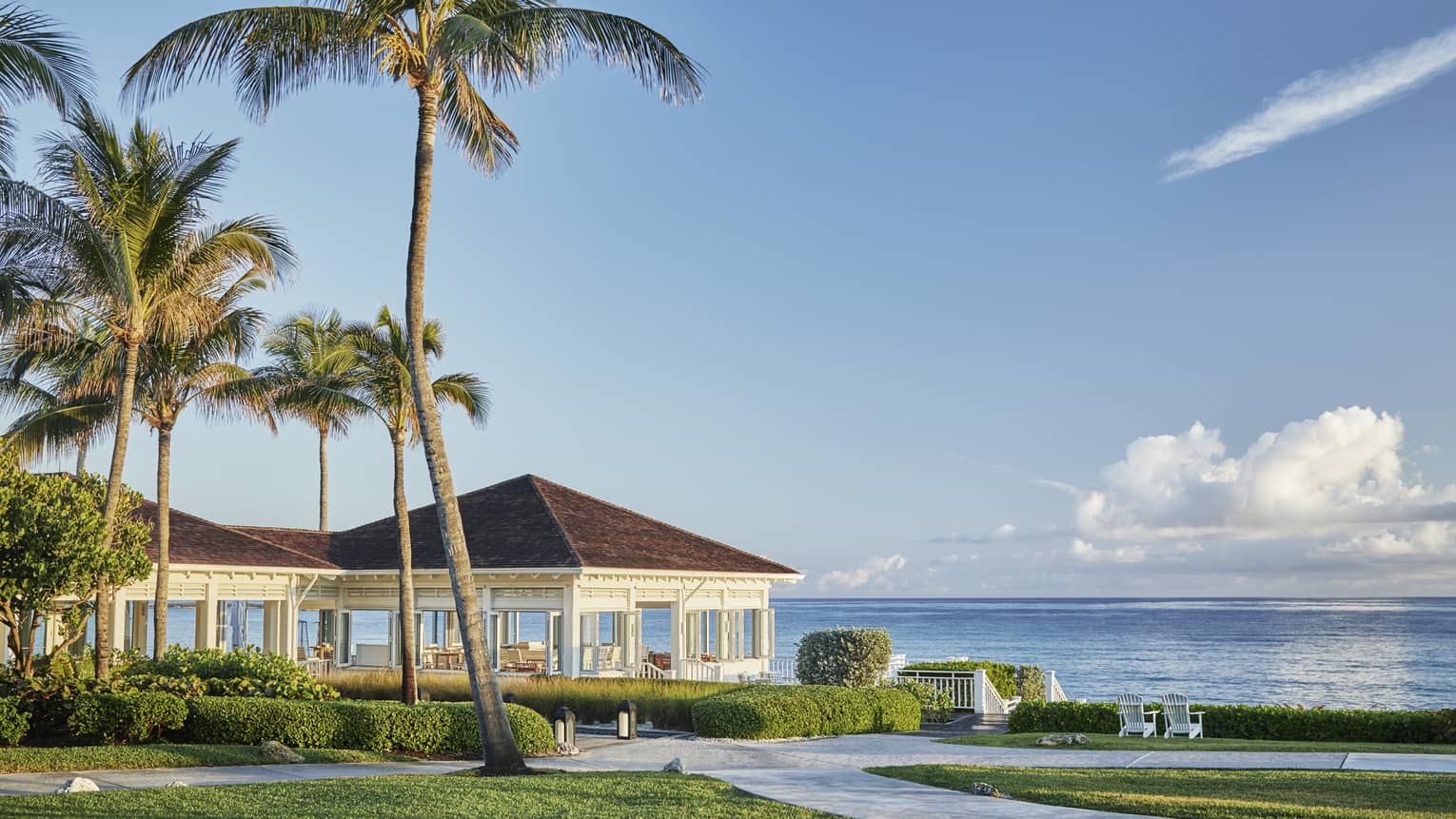 Oceanfront restaurant Dune's pavilions and palm trees, sunny skies over ocean