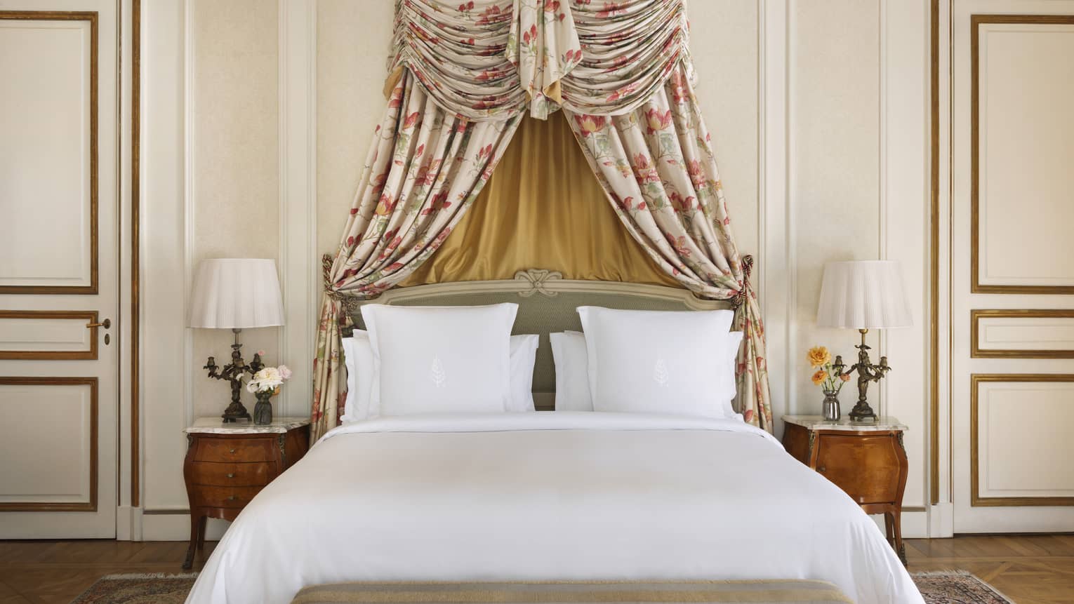 King bed with white linens and a canopy-style headboard made from floral fabric