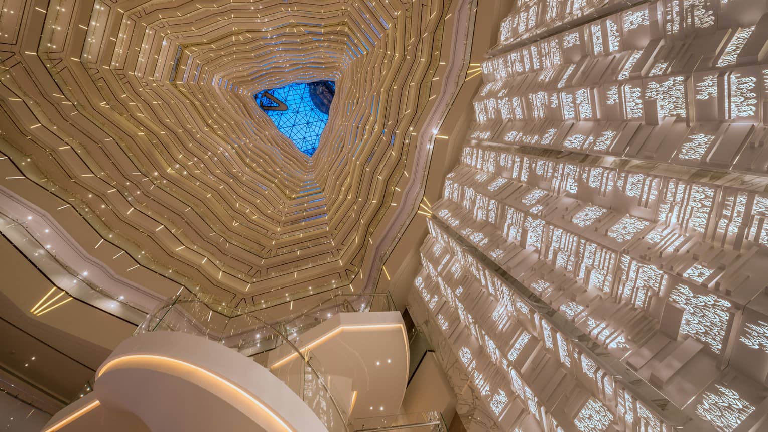 Triangular skylight seen past many floors of curved white balconies inside Four Seasons Hotel Guangzhou 