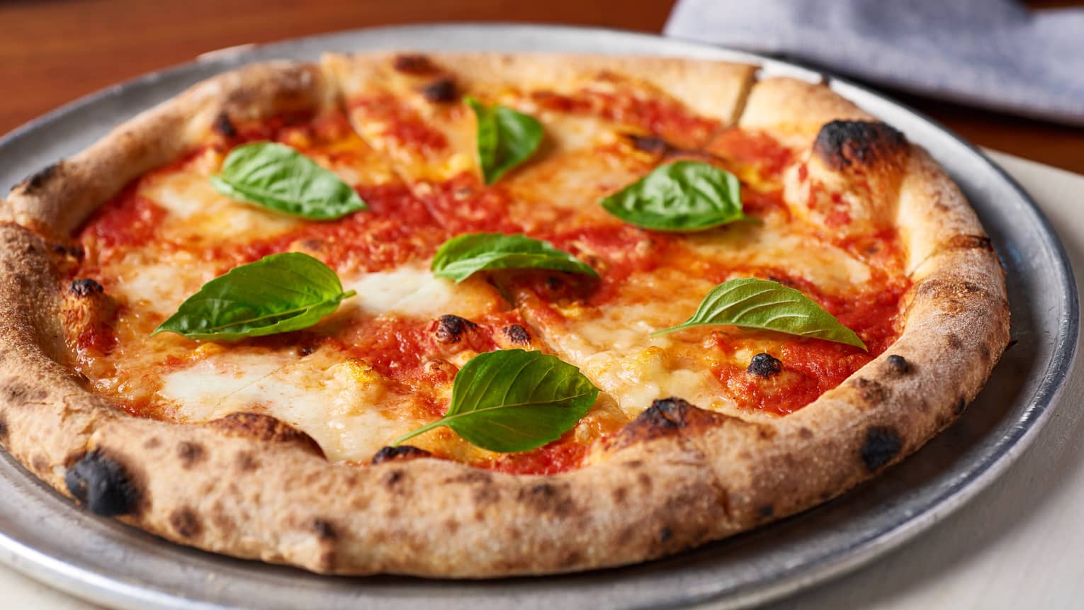 Margherita pizza with fresh basil leaves on metal pan