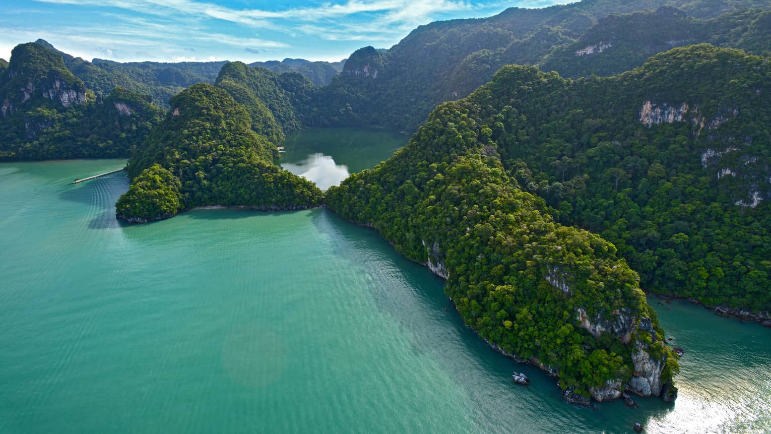 Aerial view of large green Langkawi Geoparks mountains over ocean