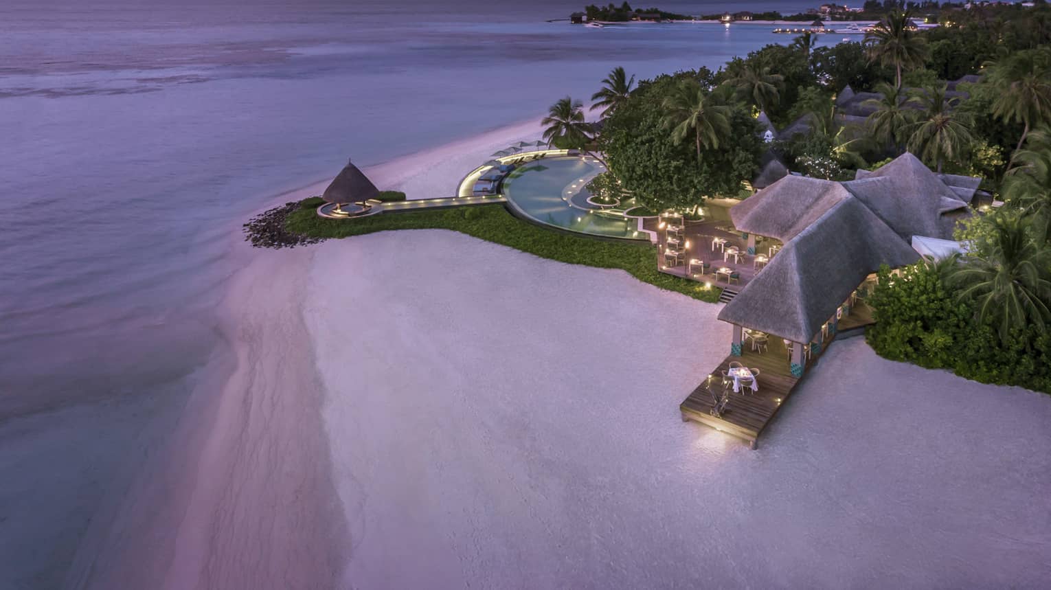 Aerial view of beach and Resort's illuminated deck with pool