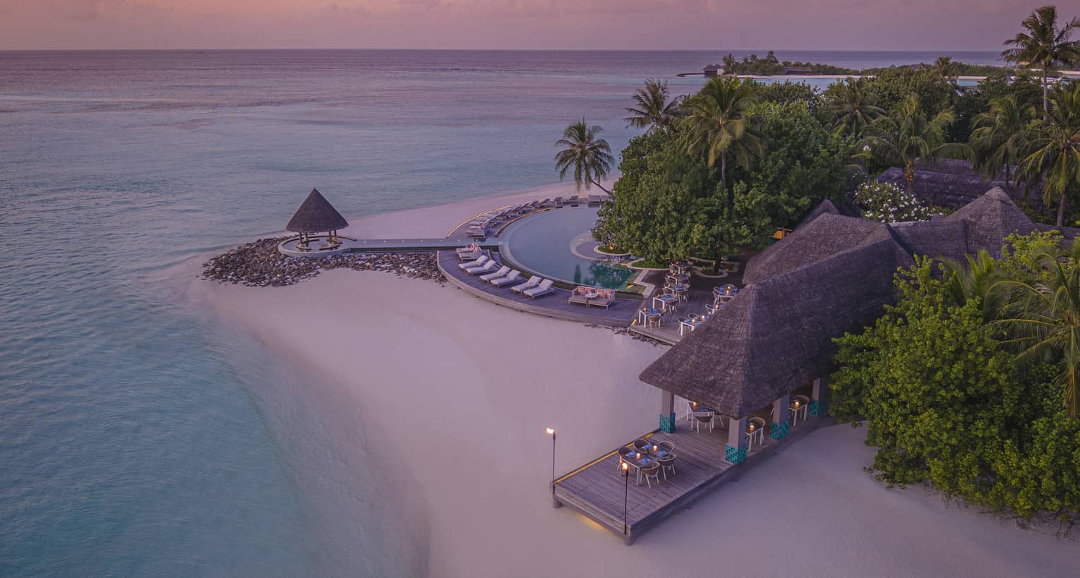 Aerial view of beachfront straw roof pavilion at sunset