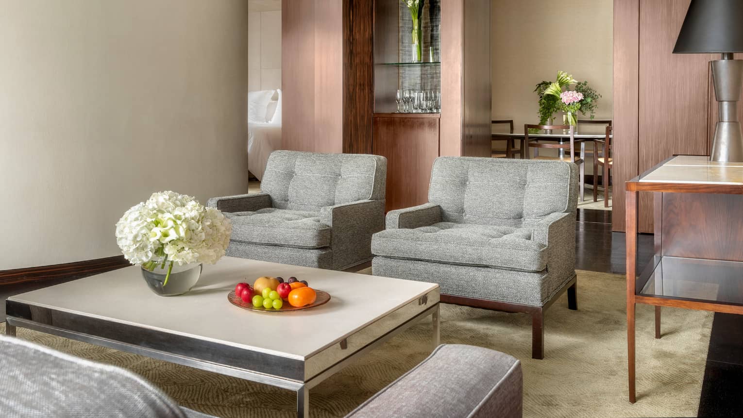 Deluxe One-Bedroom Suite living room vignette with gray club chairs and white coffee table