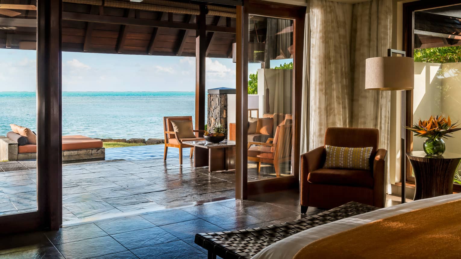 Ocean Pool Villa edge of bed, wicker bench, open wall to patio, ocean views