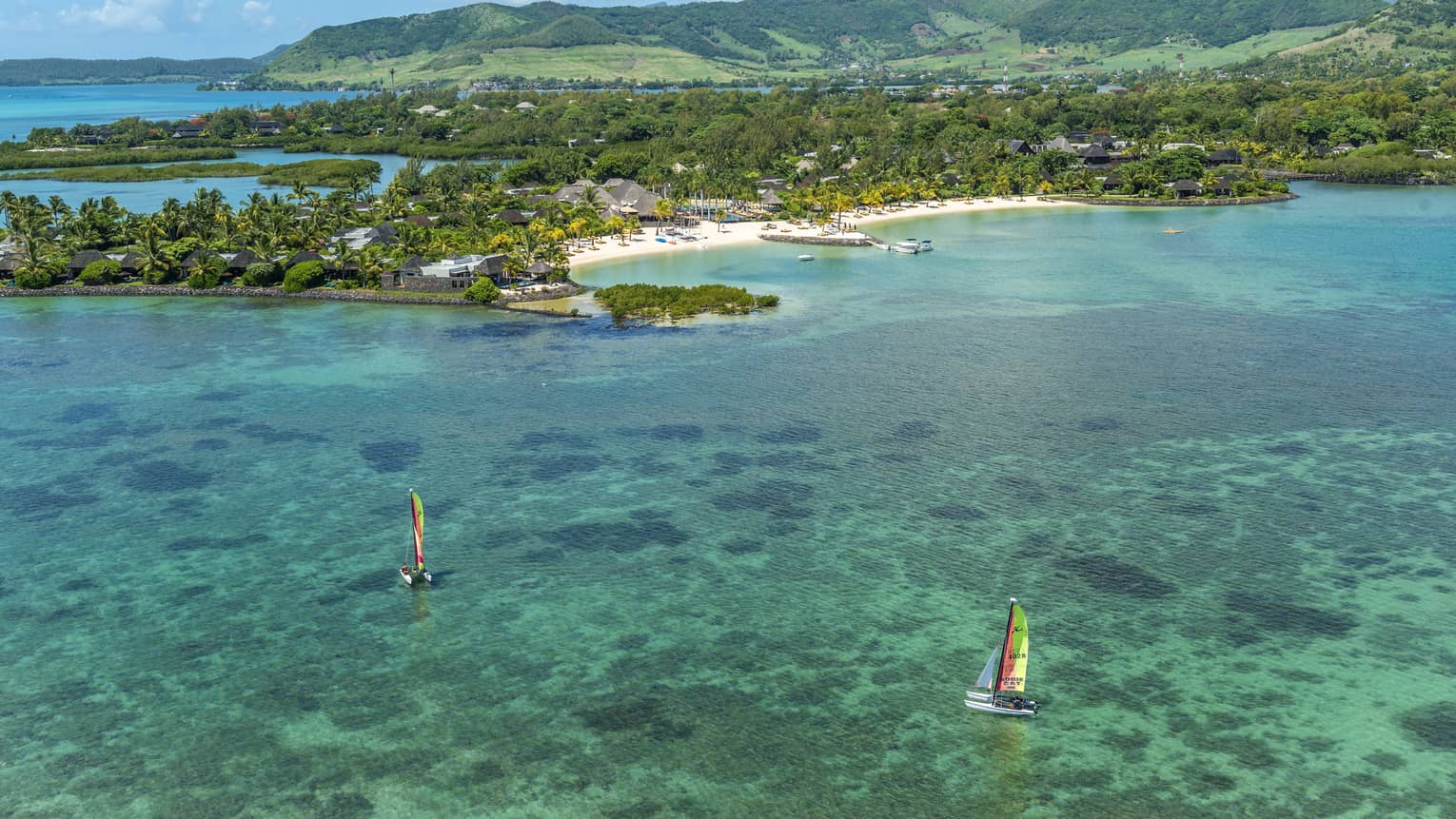 Aerial view of two colourful sailboats on turquoise water in lagoon