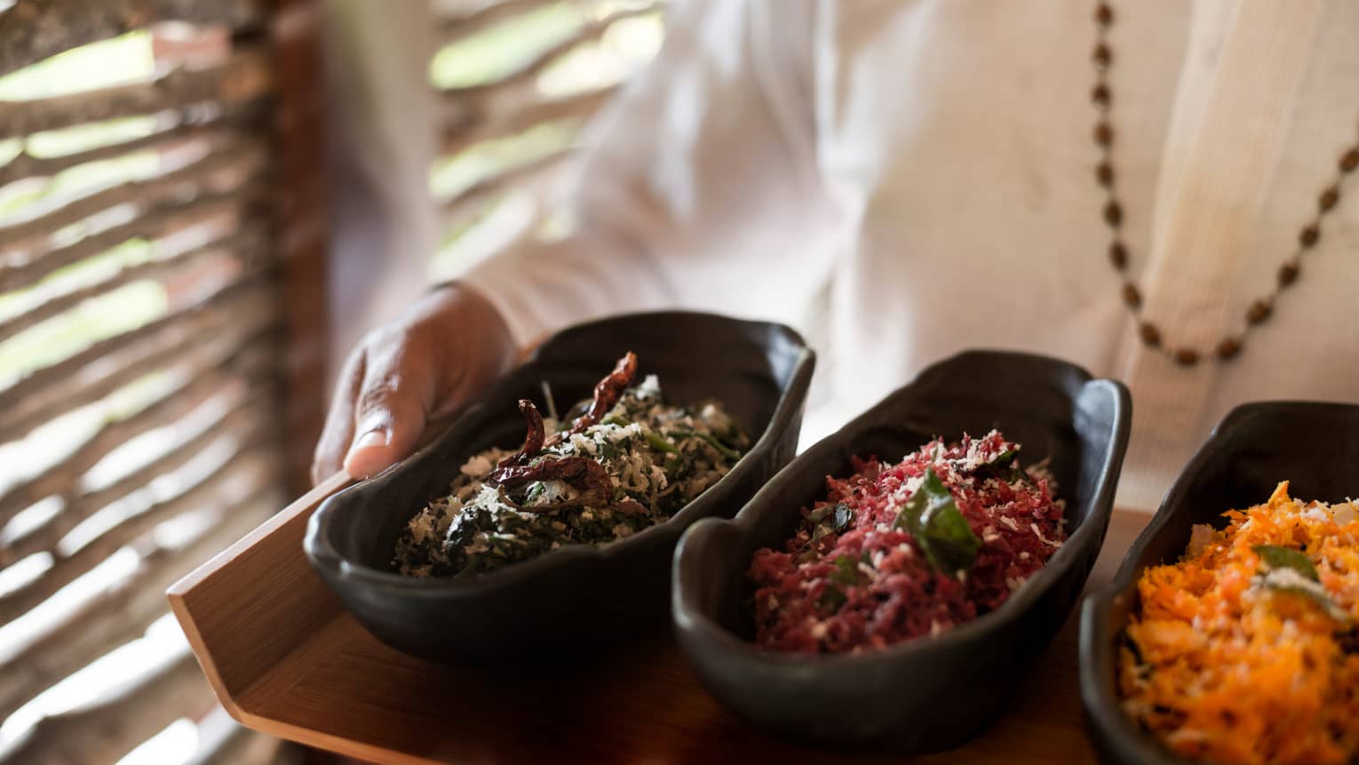 Close-up of three black dishes with colourful spices on tray