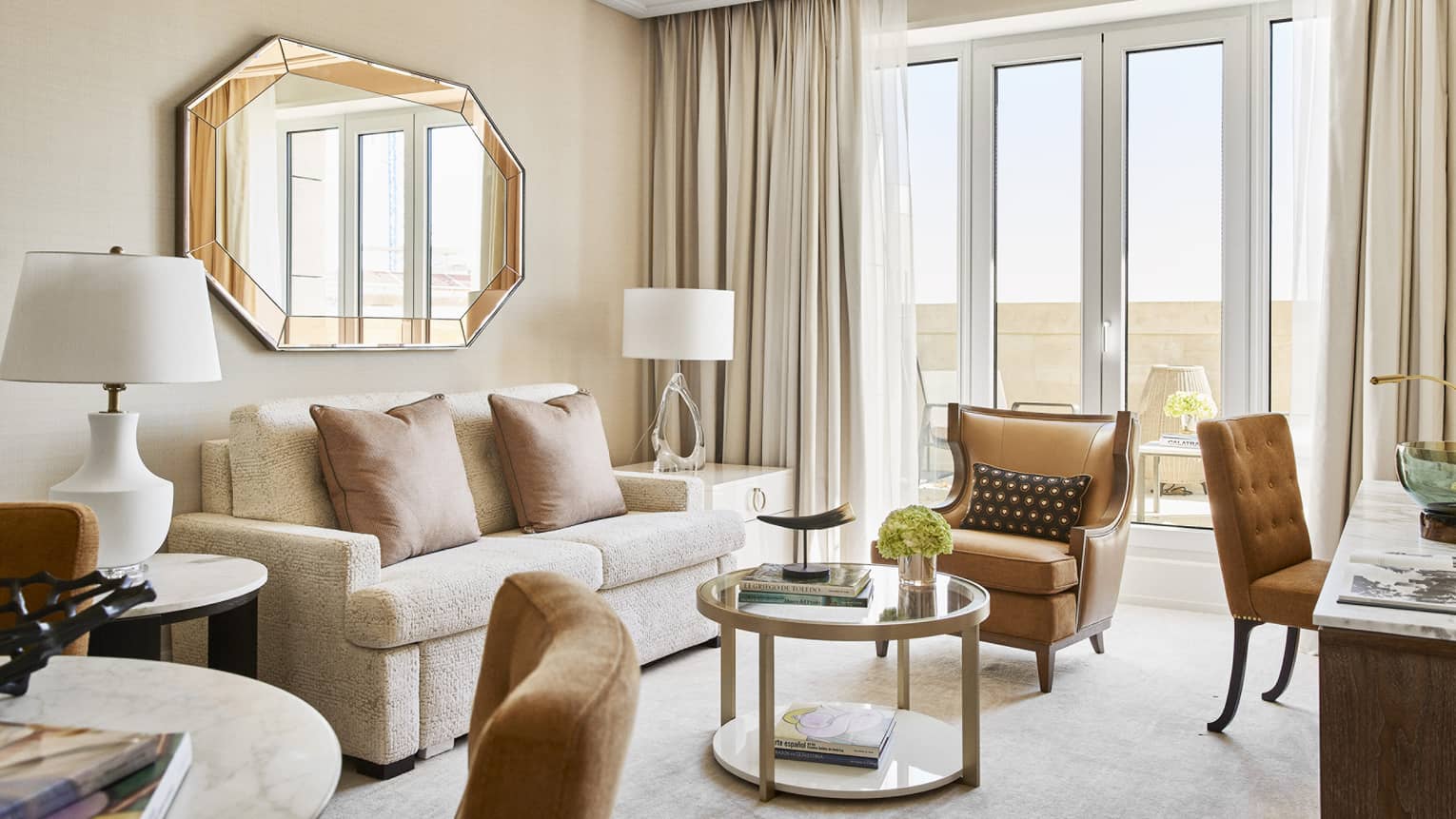 Living room with two-person sofa, gold mirror, arm chair and round coffee table
