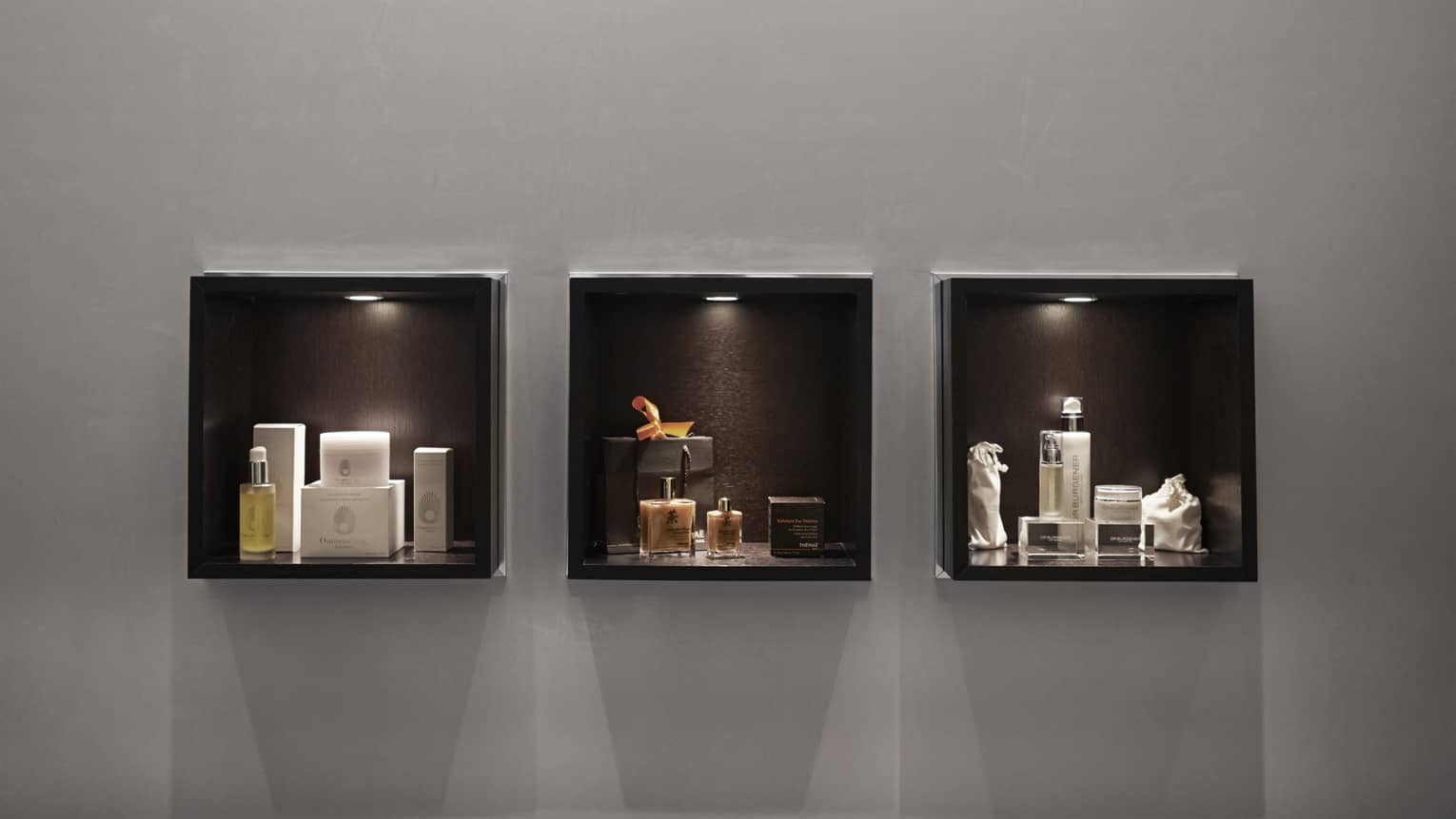 Three display boxes with spotlights showcase luxury skincare and cosmetic products. Organized and elegant, they highlight the exclusivity of the items.