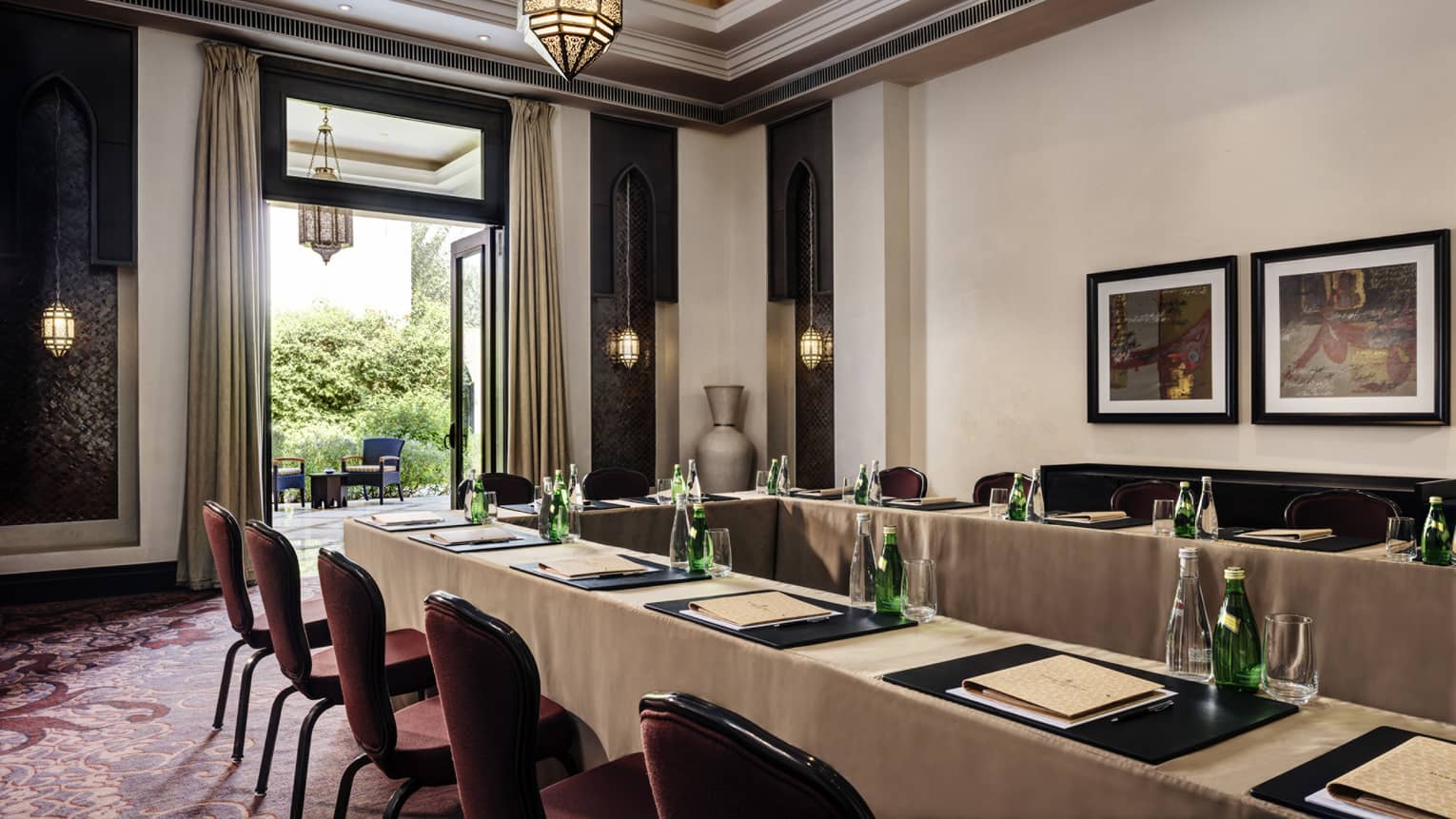 Long meeting tables, chairs under high ceiling, framed art by open patio door