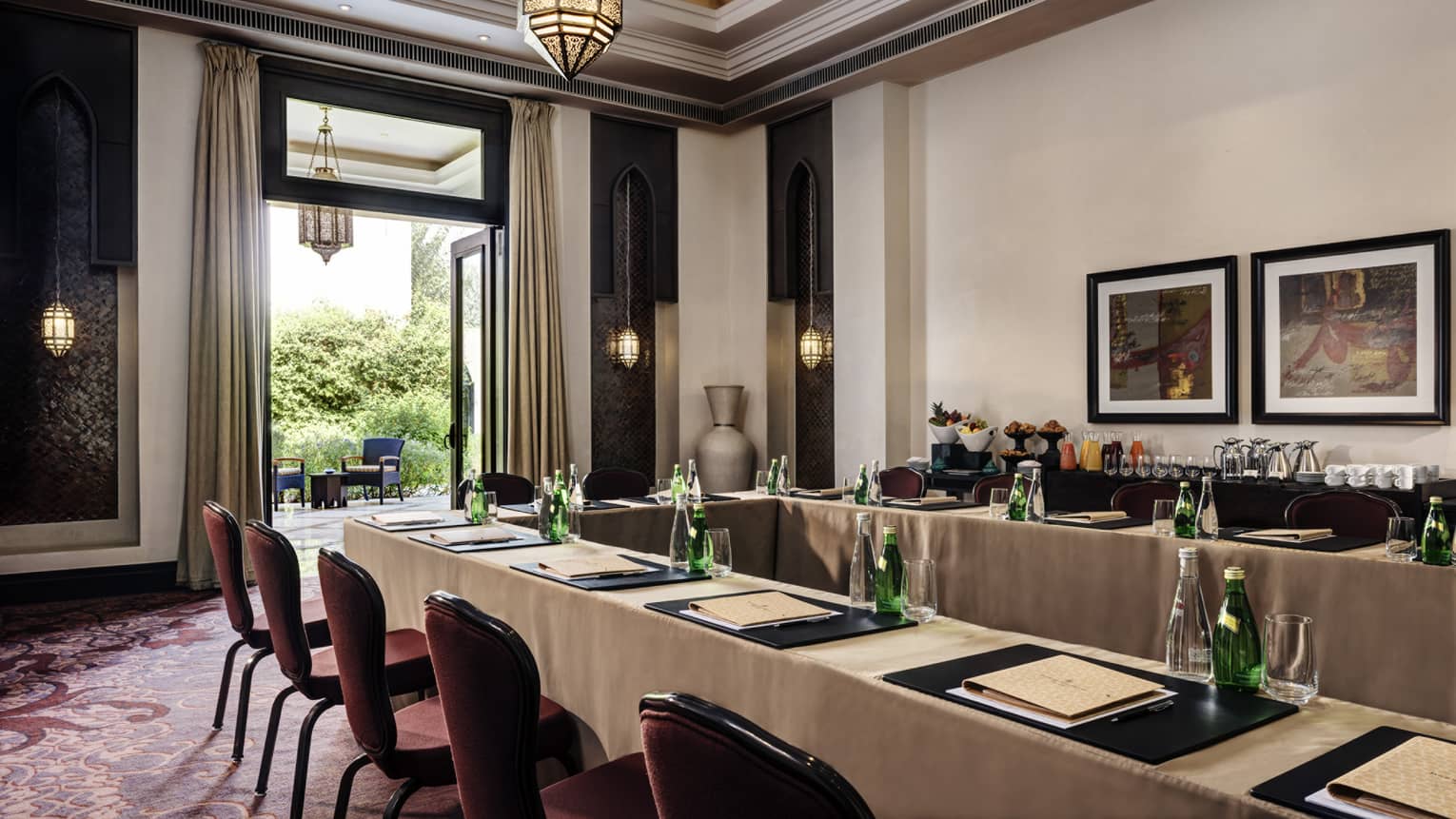Long meeting tables, chairs under high ceiling, framed art by open patio door