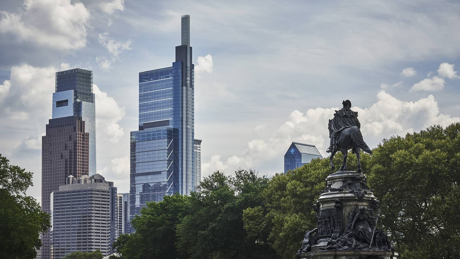 Sky rises in downtown Philadelphia, with statue and trees in foreground