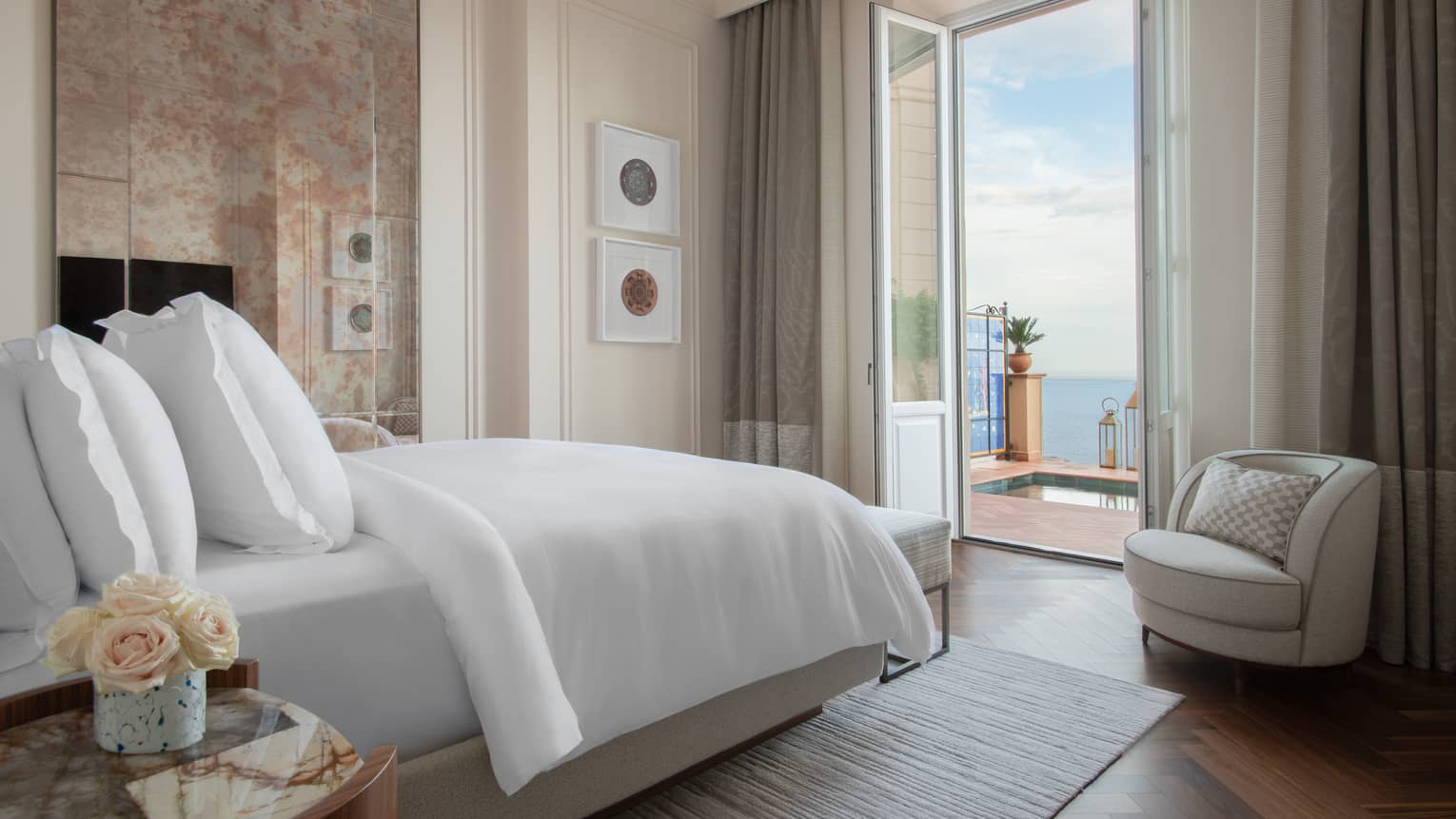 Bedroom with bed facing opened doors to sea-view terrace with plunge pool