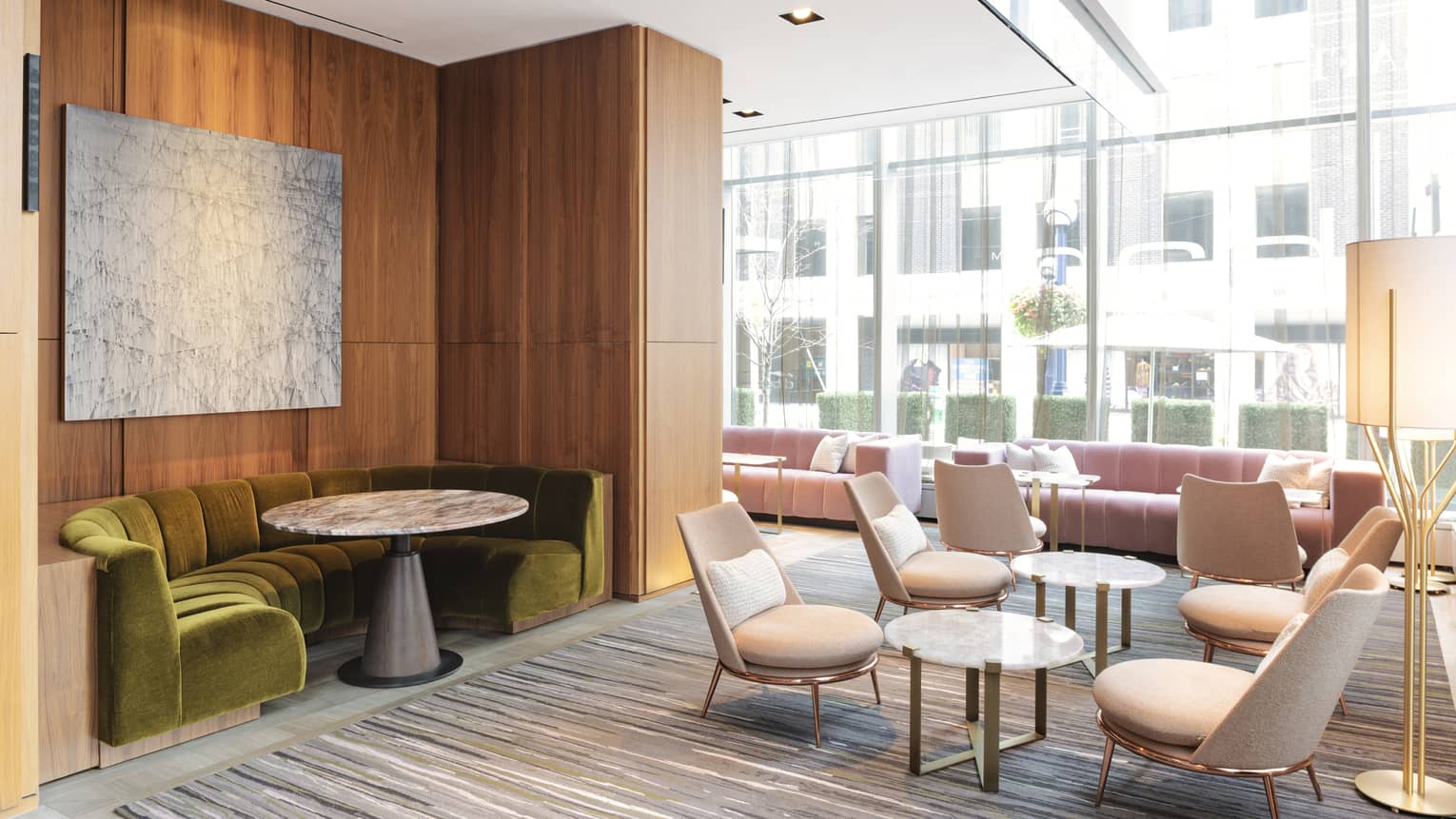 a lounge with upholstered chairs and a round sofa, marble tables and wooden accents 