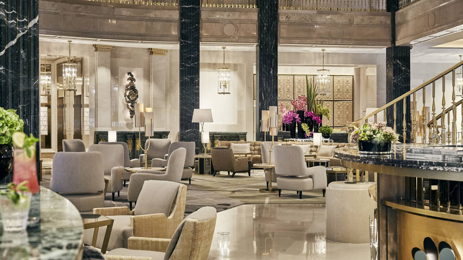 2-story columned lobby with marble flooring, gold accents and leather chairs