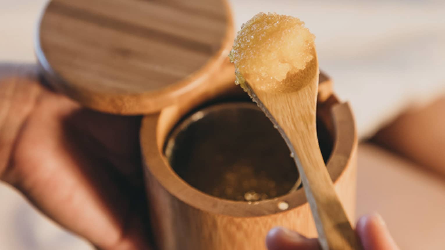 A spa staff member scoops some sugar scrub out of a bamboo container in Hawaii
