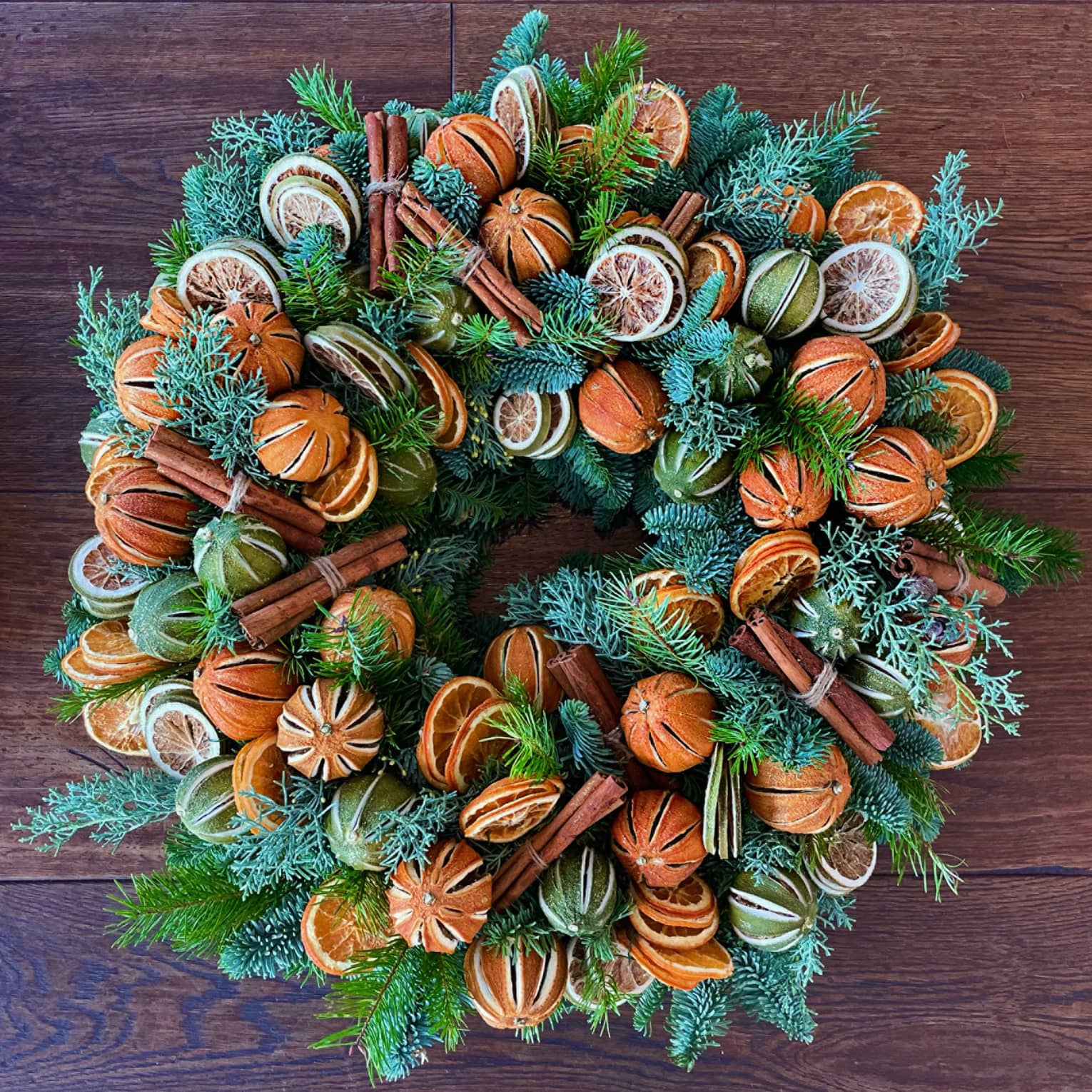 A wreath with greens and oranges.